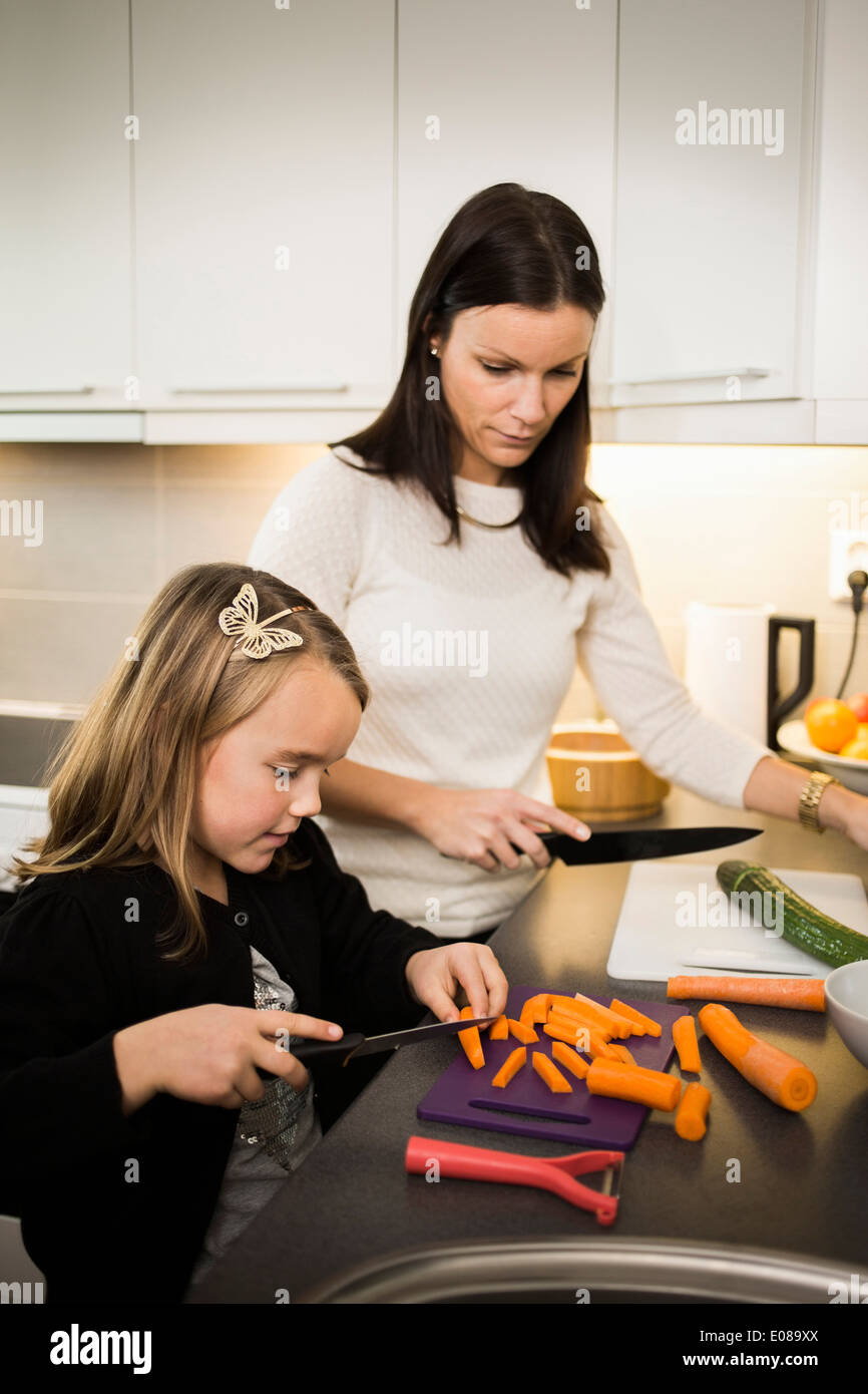 Mutter und Tochter Schneiden von Gemüse in der Küche Stockfoto