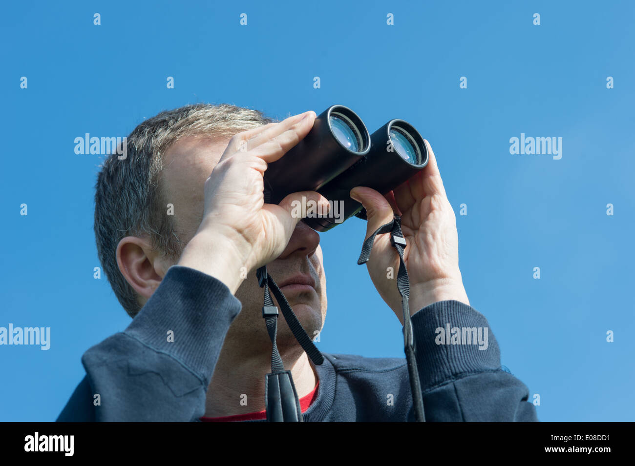 Blick durch ein Fernglas mit blauem Himmel hinter männlich Stockfoto