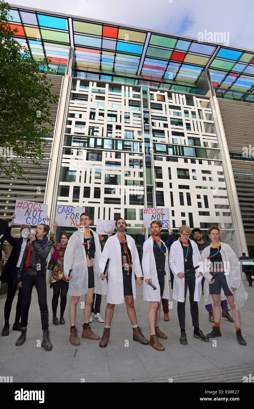 London, UK. 6. Mai 2014. Act Up Docs nicht Cops Einwanderungsgesetz protestieren im Home Office in London mit Demonstranten verkleidet als Ärzte zu Polizei abstreifen. ACT UP London kämpft gegen zwei Klauseln in der Immigration-Rechnung, die dazu dienen, Kosten für Gesundheitsdienstleistungen einführen, Ärzte in Grenzbeamten verwandeln und HIV-Infektion erhöhen. Bildnachweis: Paul Brown/Alamy Live-Nachrichten Stockfoto