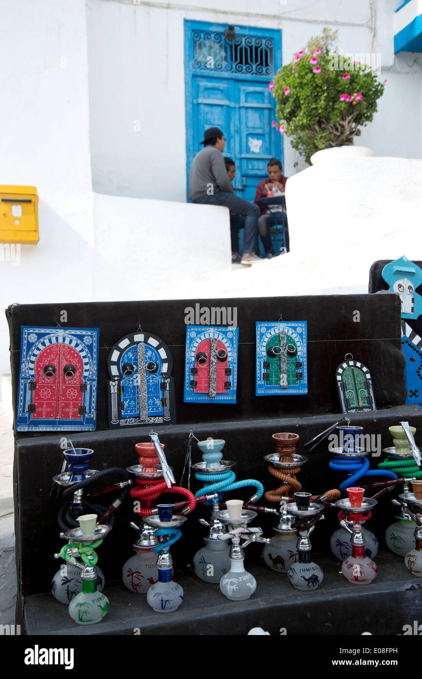 Sidi Bou Said, Tunesien 2014. Touristische Souvenirs - Wasserleitungen und verzierte Türen - Angebote unter einem Café, wo junge Männer sitzen. Stockfoto