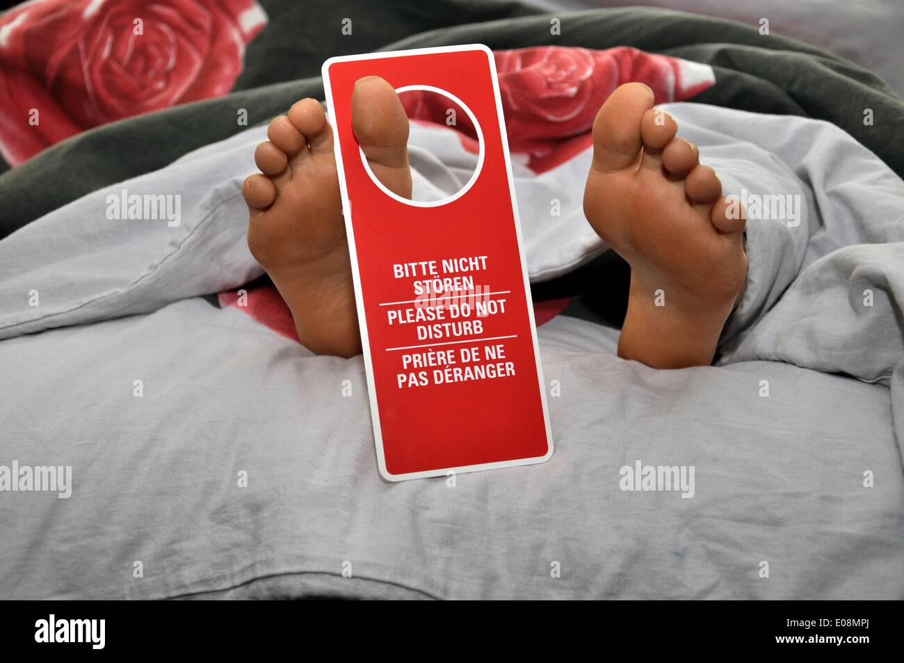Illustration - Ein Schild mit der Aufschrift "Bitte nicht stoeren", "Bitte nicht stören" und "Priere de ne pas deranger" hängt in Deutschland am 17. Juli 2011 an einem Fuß, der unter einer Decke hinausschaut. Fotoarchiv für Zeitgeschichte - KEIN KABELDIENST Stockfoto