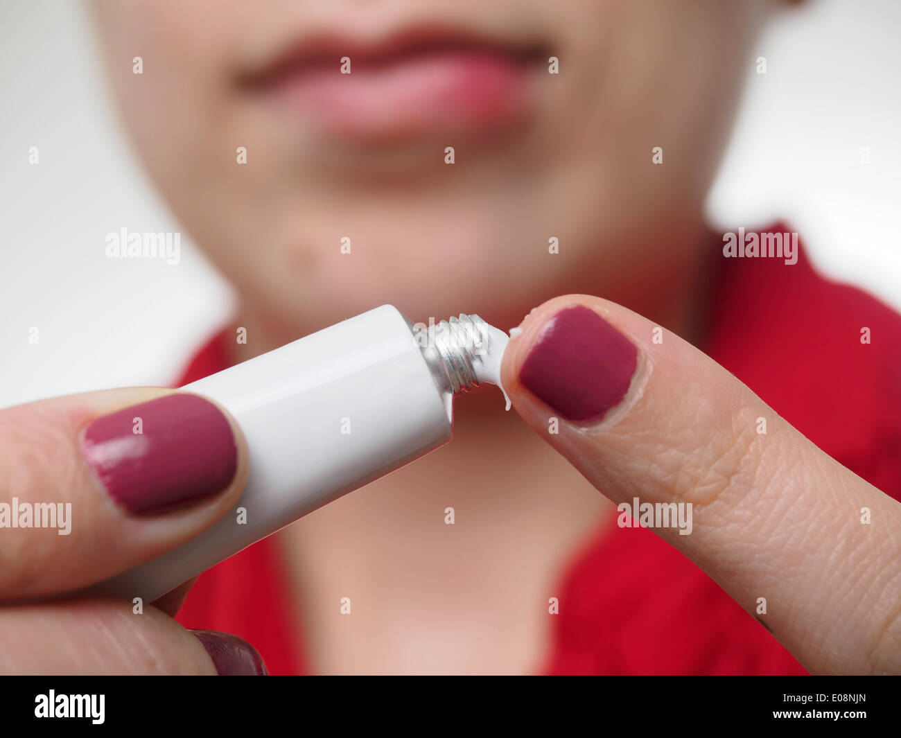 Junge Frau setzen Salbe zur Behandlung von Herpes Simplex auf ihrer Unterlippe Stockfoto
