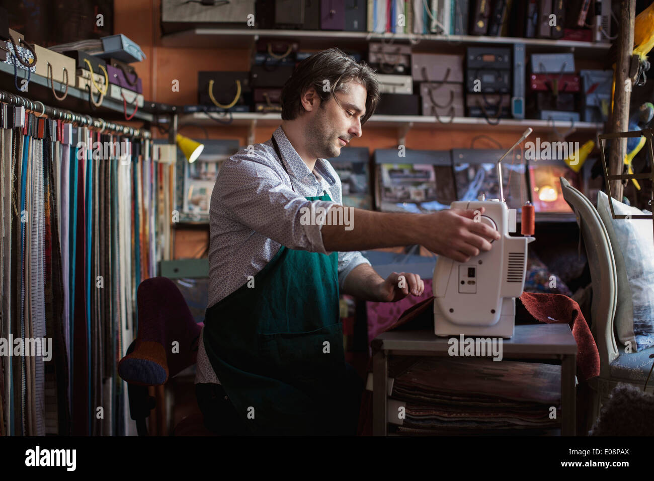 Männliche Schneider mit Nähmaschine im Designstudio Stockfoto