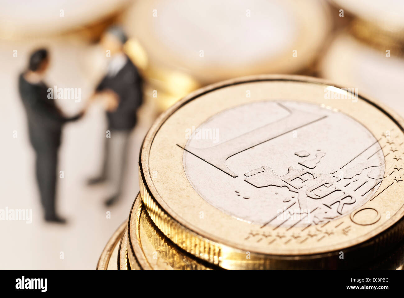 Euro-Münzen und zwei Geschäftsleute im Hintergrund Stockfoto