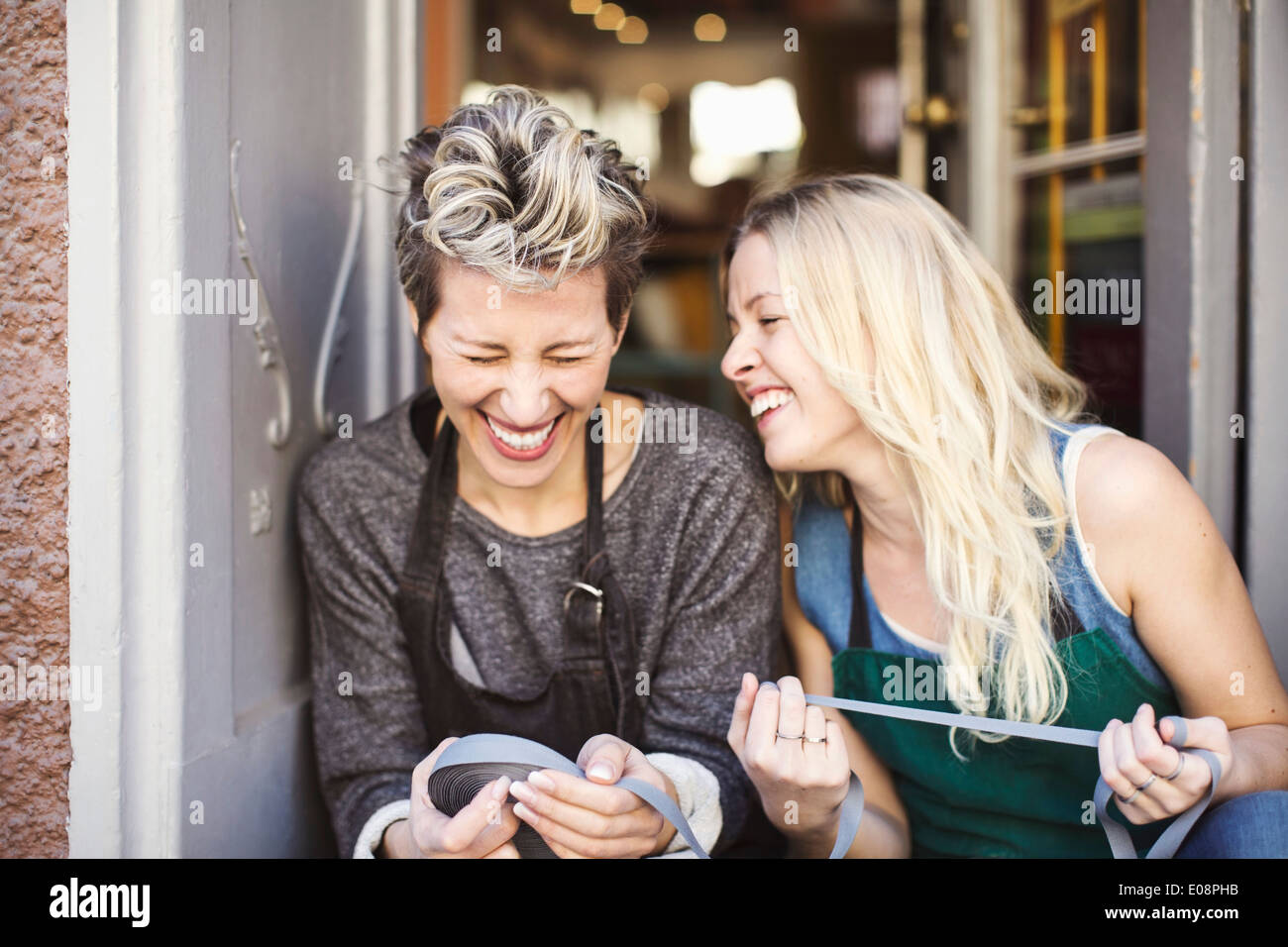 Glücklich Modedesigner mit Multifunktionsleiste Spule am Studio Tür sitzen Stockfoto