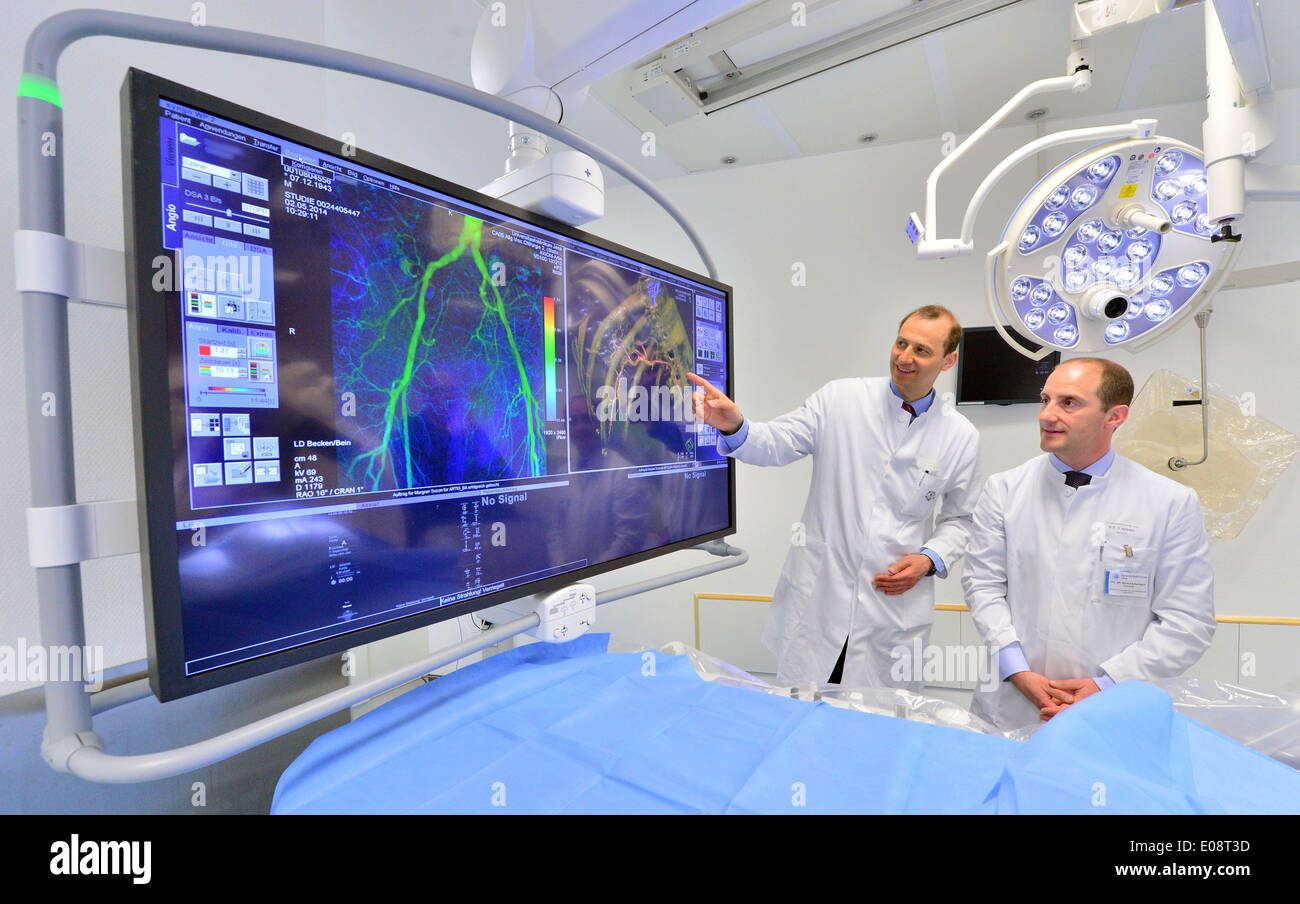 Jena, Deutschland. 6. Mai 2014. Direktor der Radiologie Zentrum Ulf Teichgraeber (L) und leitender Oberarzt Rene Aschenbach Blick auf das neue Angiographiesystem auf ein Krankenhaus-Mitarbeiter am Institut für diagnostische und Interventionelle Radiologie (Cesari) am Universitätsklinikum in Jena, Deutschland, 6. Mai 2014. Es ist das erste Krankenhaus in deutscher Sprache, Angiographie für die Patientenversorgung zu verwenden. Ein flexiblen Roboterarm bewegt sich um den Patienten, so dass für Organe und Blutgefäße, leichter und schneller aus verschiedenen Blickwinkeln betrachtet werden. Foto: MARTIN SCHUTT/Dpa/Alamy Live News Stockfoto