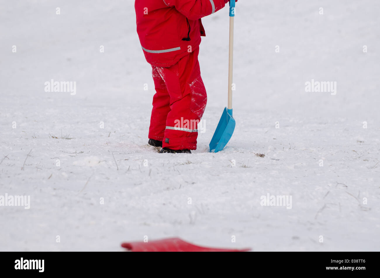 Kind Stand mit großen Schneeschaufel rot wasserdichte Kleidung im Freien im winter Stockfoto