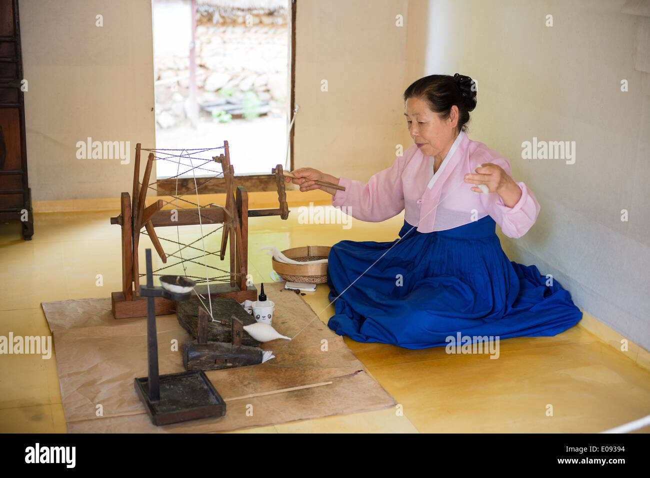 Eine ältere Frau Spinnen von Wolle auf traditionelle Weise in einer koreanischen Folk Village Stockfoto