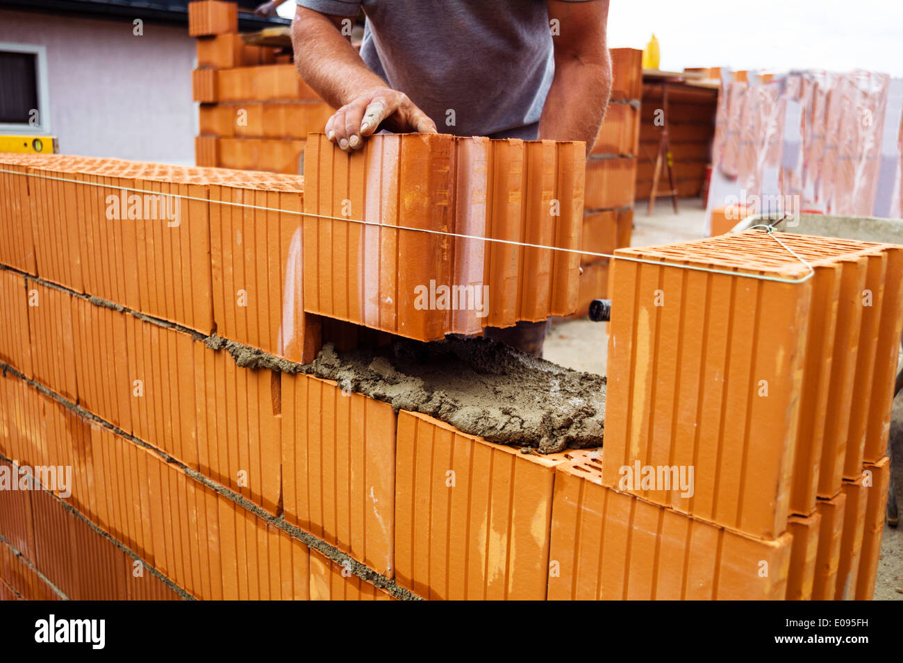 Anonyme Bauarbeiter auf der Baustelle mit dem Bau eines Hauses stellt eine Mauer aus Stein. Mauer von einem mas Stockfoto