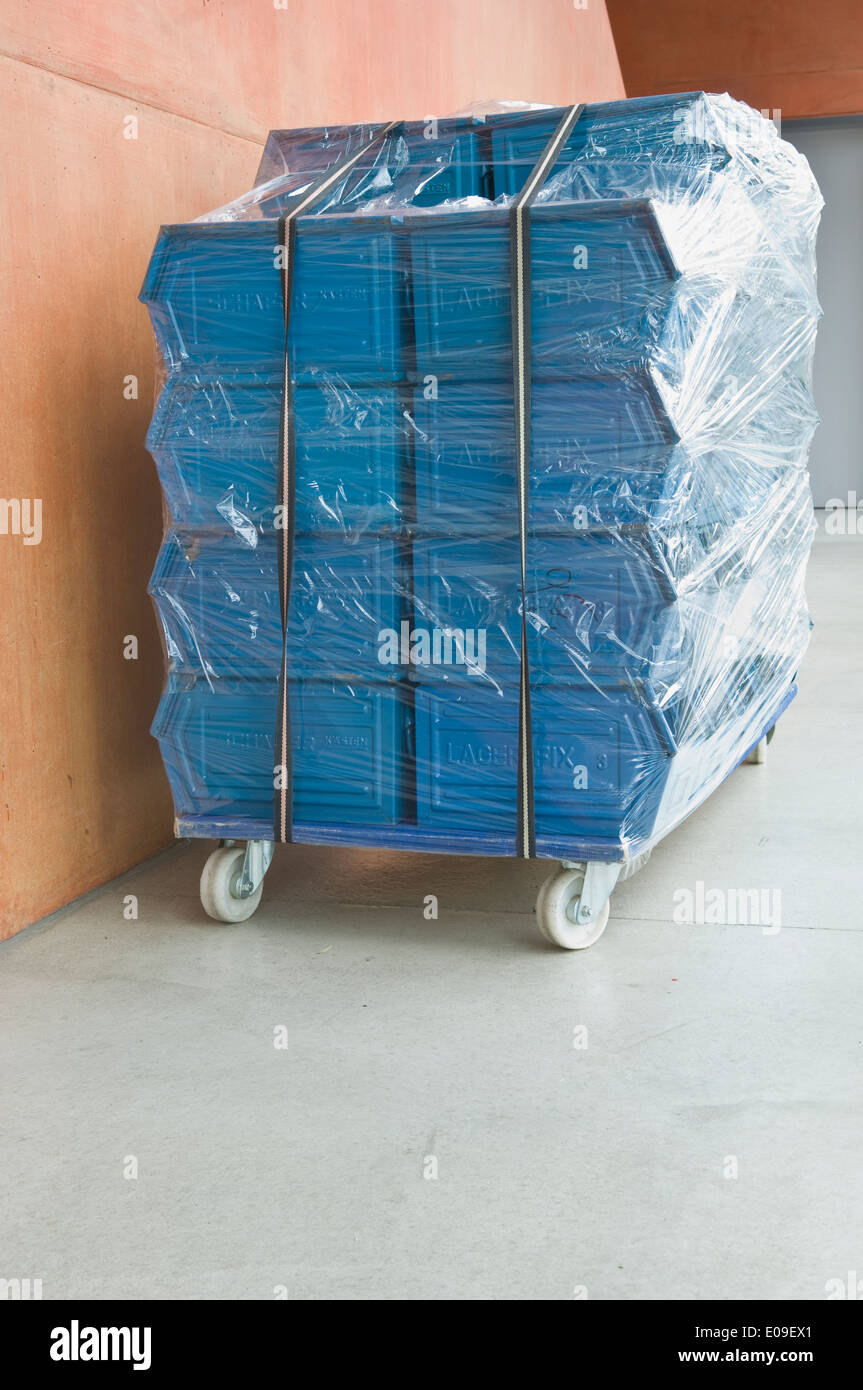 Stapel von blau Metall-Boxen stehen auf Creeper Dolly in Folie verpackt Stockfoto