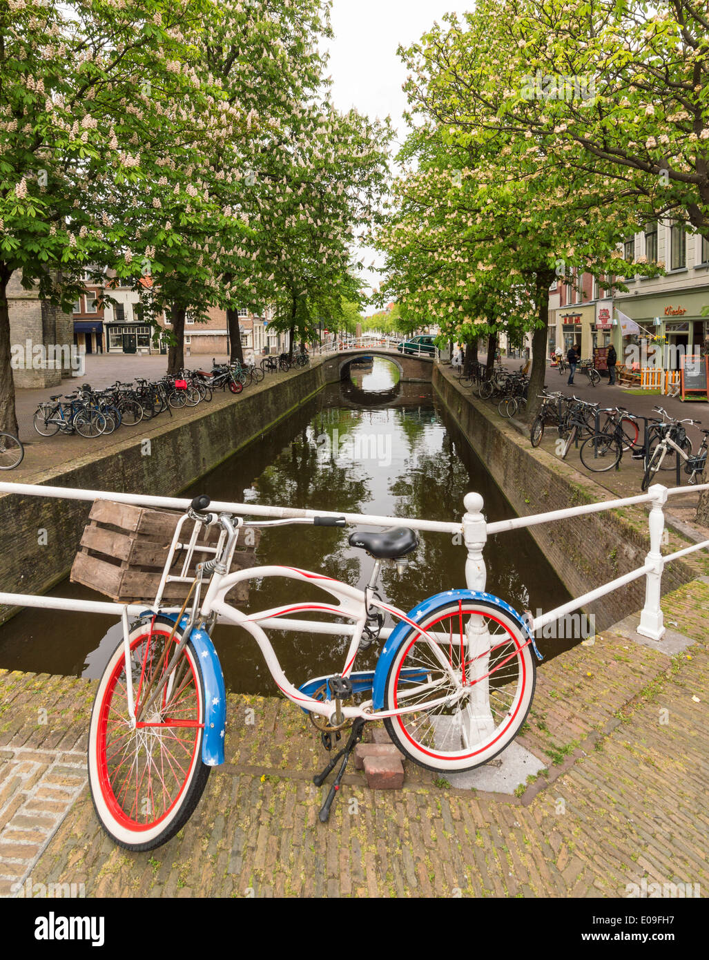 KANAL IN DER NÄHE DER MARKTPLATZ IN DELFT HOLLAND MIT ROT, WEIß UND BLAU FAHRRAD UND ROSSKASTANIE BÄUME IM FRÜHLING Stockfoto