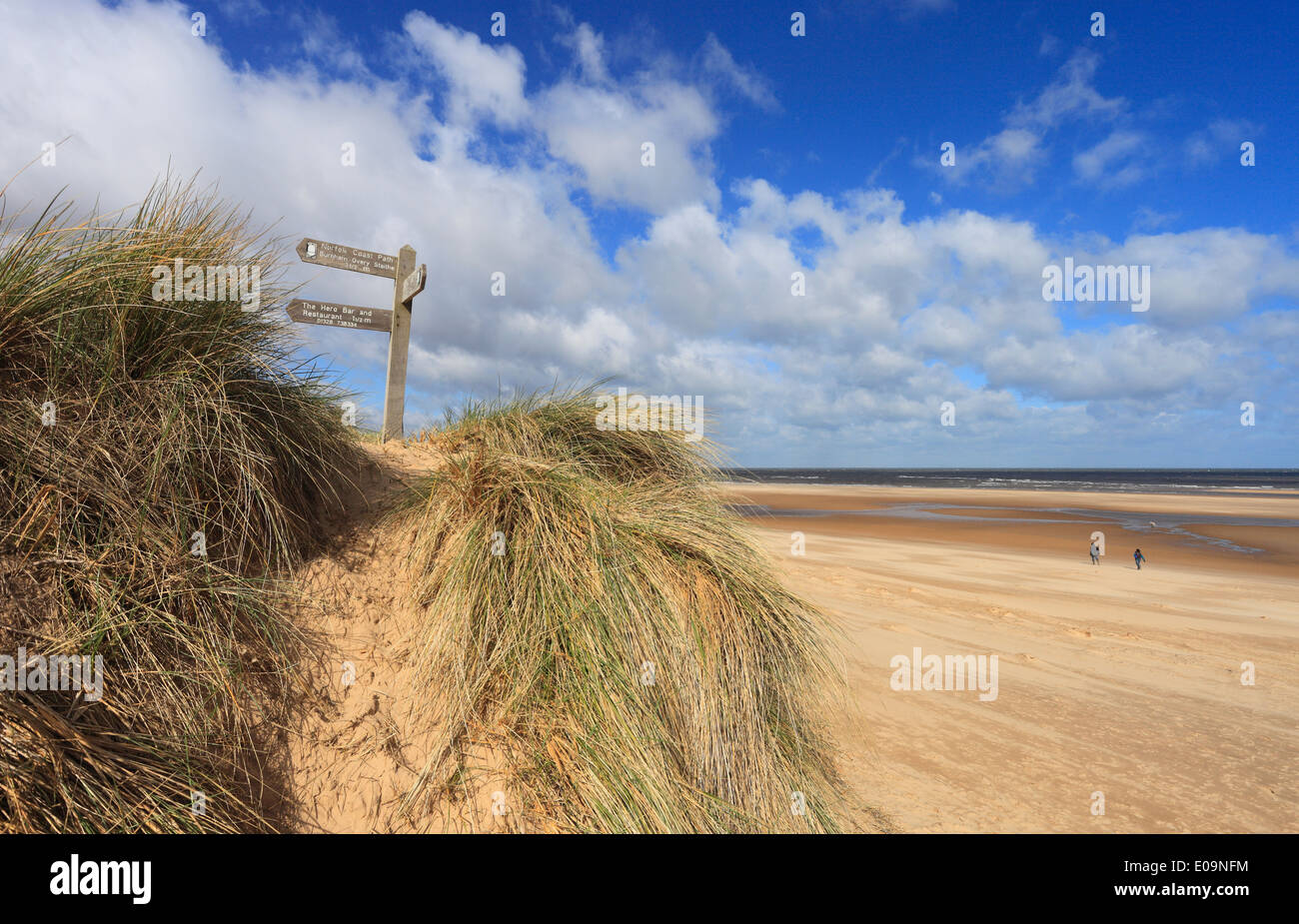 Ein paar und ein Hund zu Fuß auf dem Sand am Burnham Overy an der Nordküste #Norfolk. Stockfoto