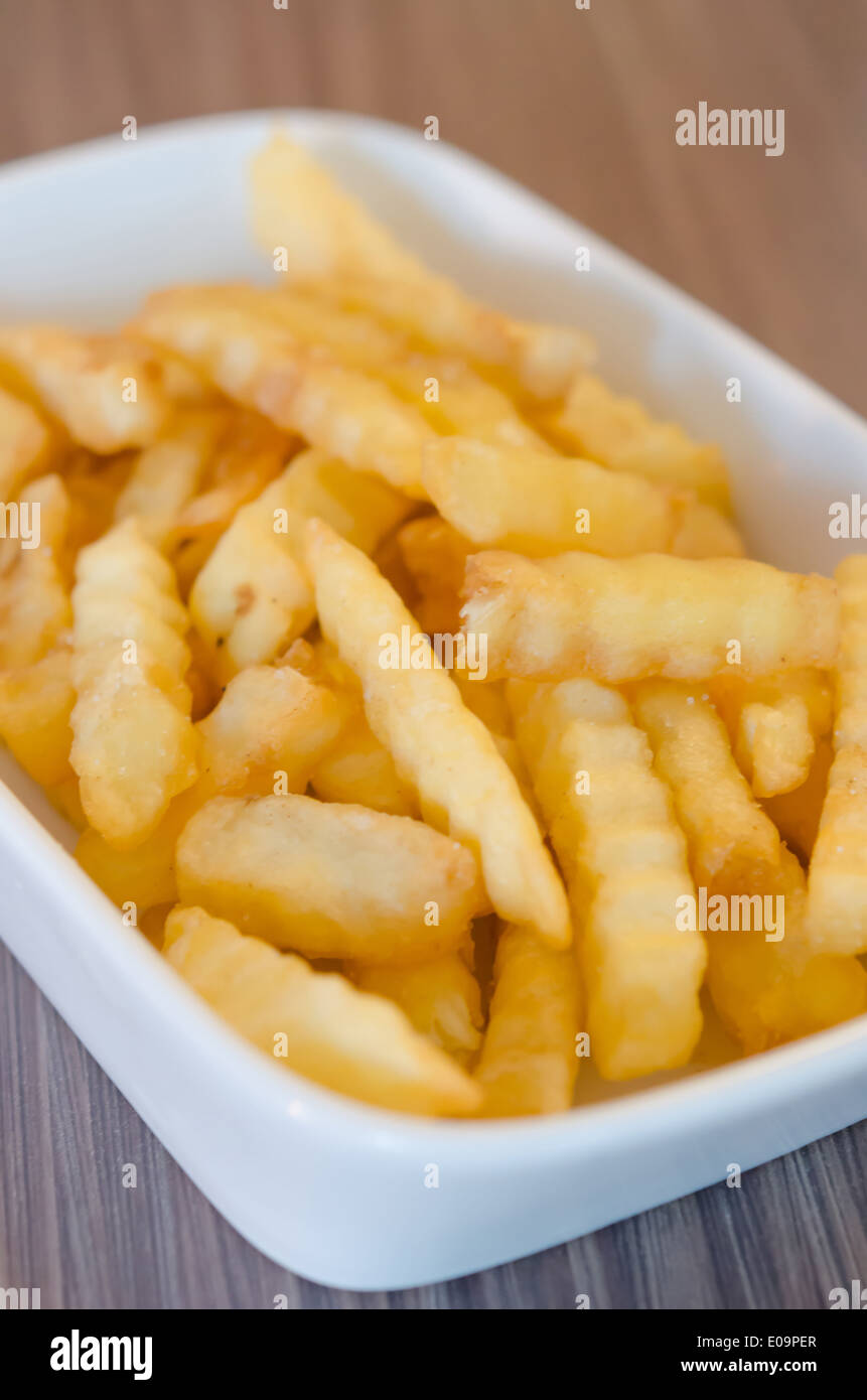 Schüssel mit Pommes Frites auf Holztisch Stockfoto