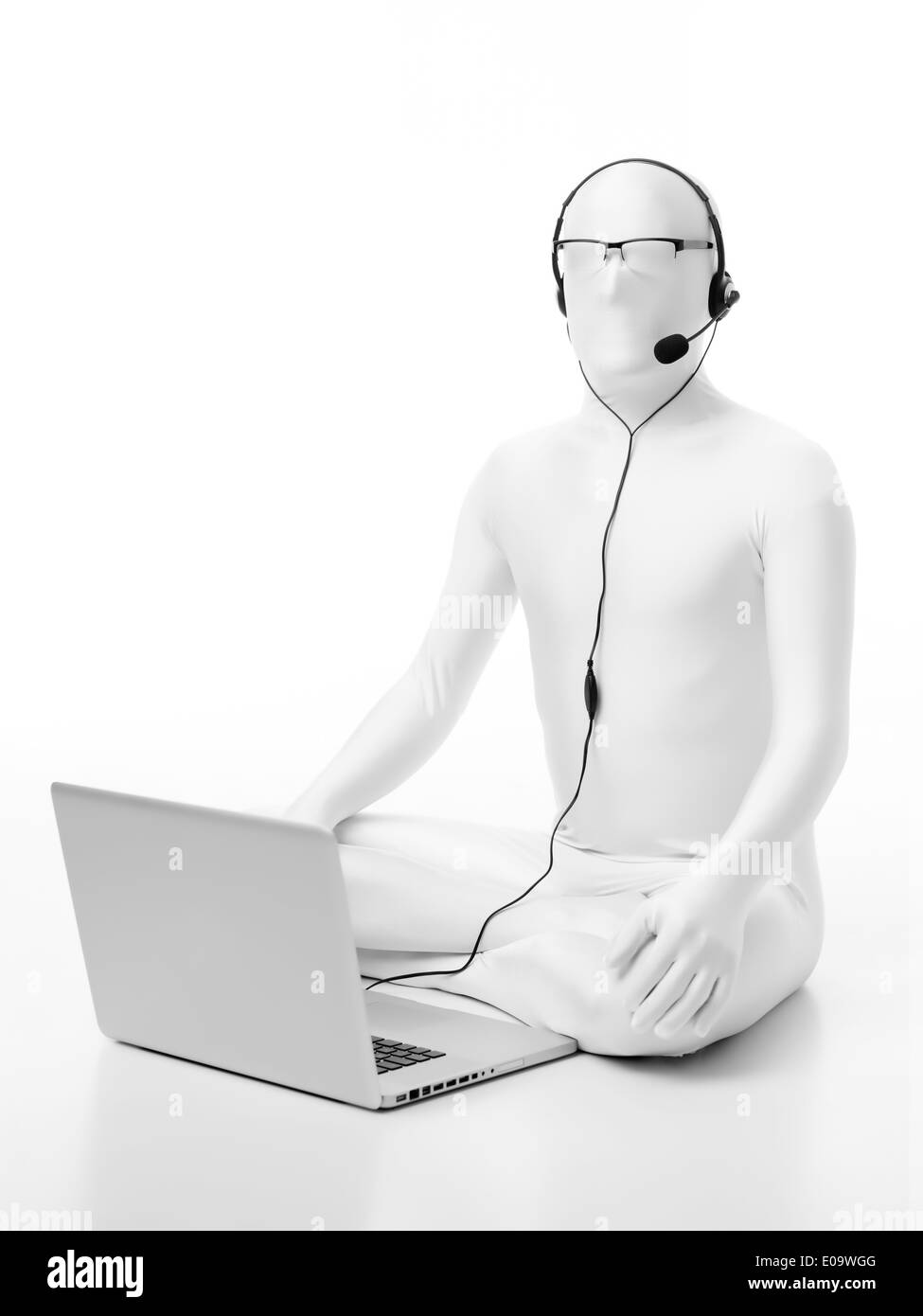 gesichtslose Mann gekleidet in weißen sitzen auf dem Boden mit einem Laptop Kopfhörer Mikrofonkopf und Brille Stockfoto