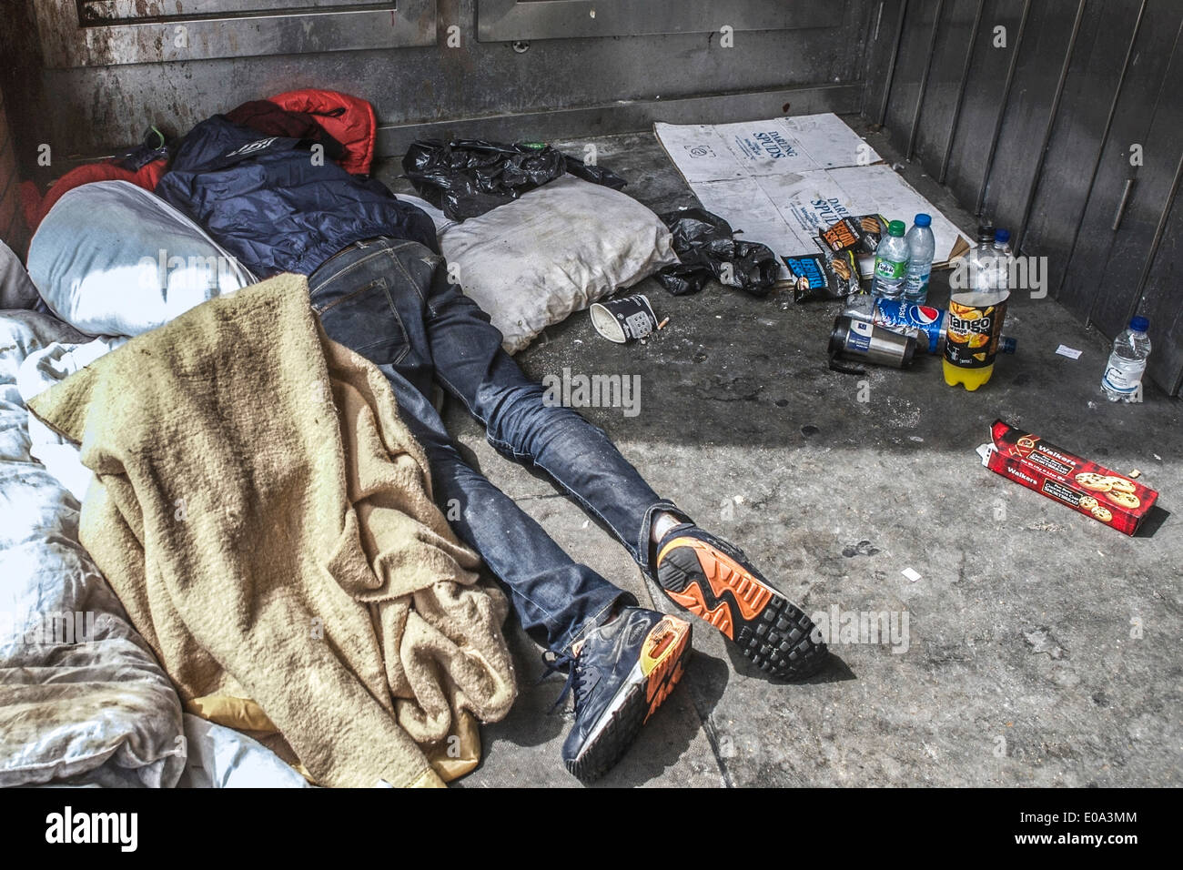 Tramp schlafen in einem Türrahmen, mit Decke mit Müll umgeben; in London, UK. Obdachlose in Großbritannien. Stockfoto