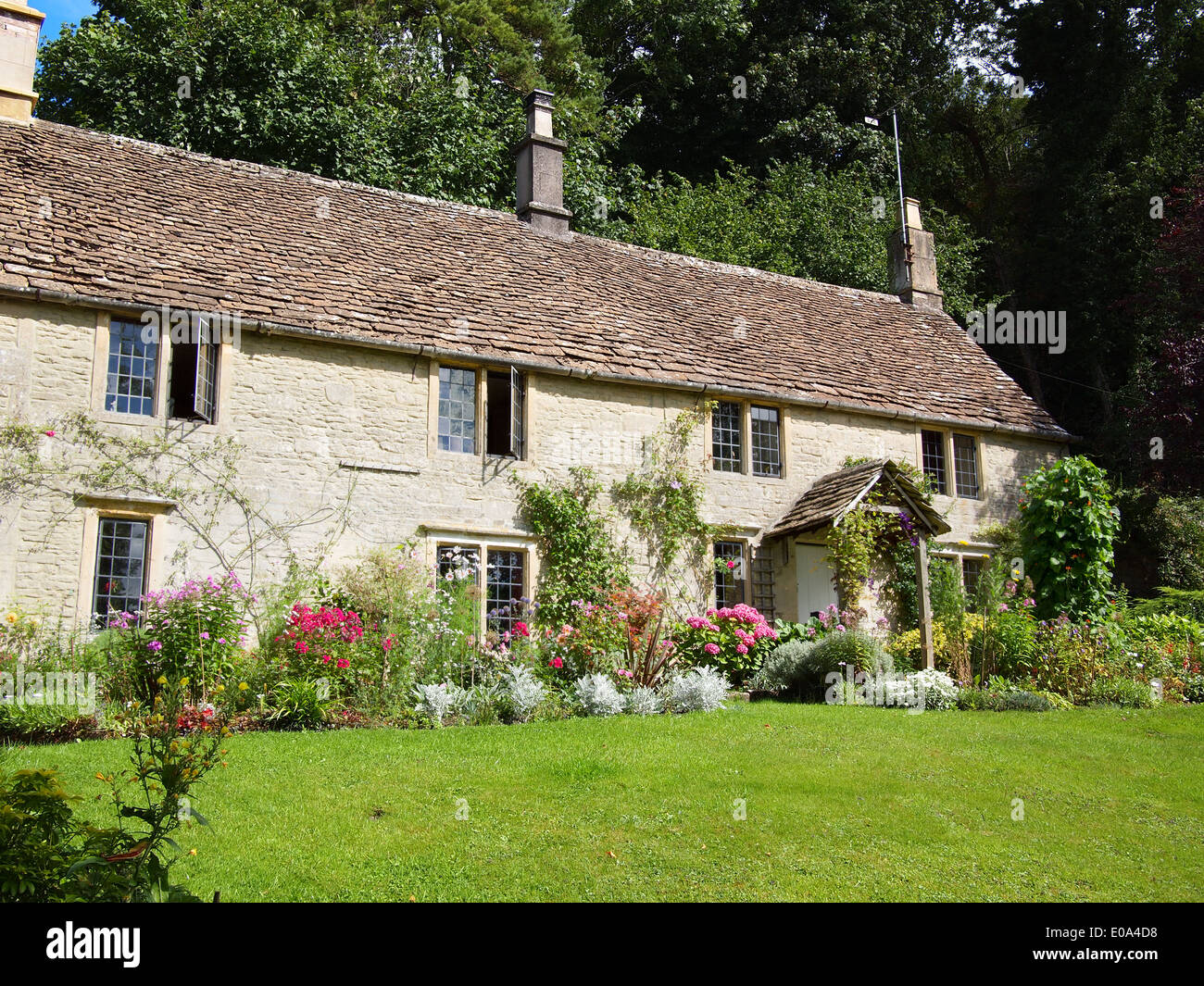 Einem englischen Cottage aus Cotswold Stein mit Steinplatten auf dem Dach mit einem Garten voller Blumen in Großbritannien gebaut. Stockfoto