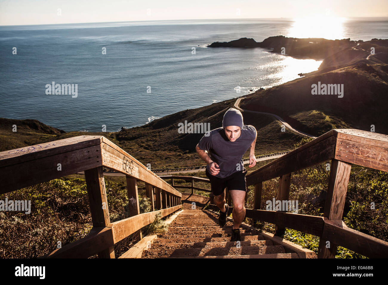 Junger Mann läuft Küsten Treppe bei Sonnenuntergang Stockfoto