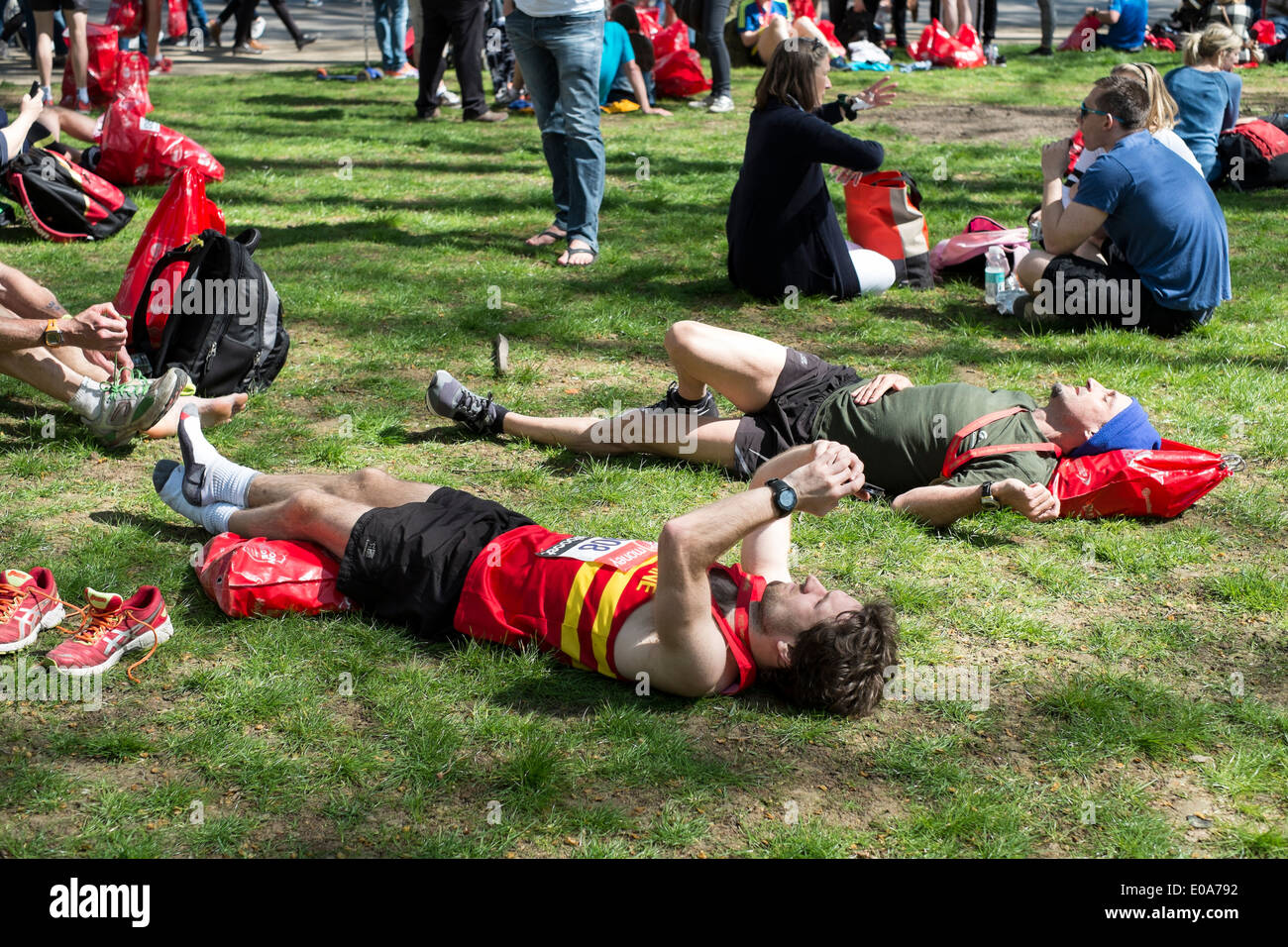 Konkurrenten im 2014 London Marathon entspannen, erschöpft im Ziel. Stockfoto