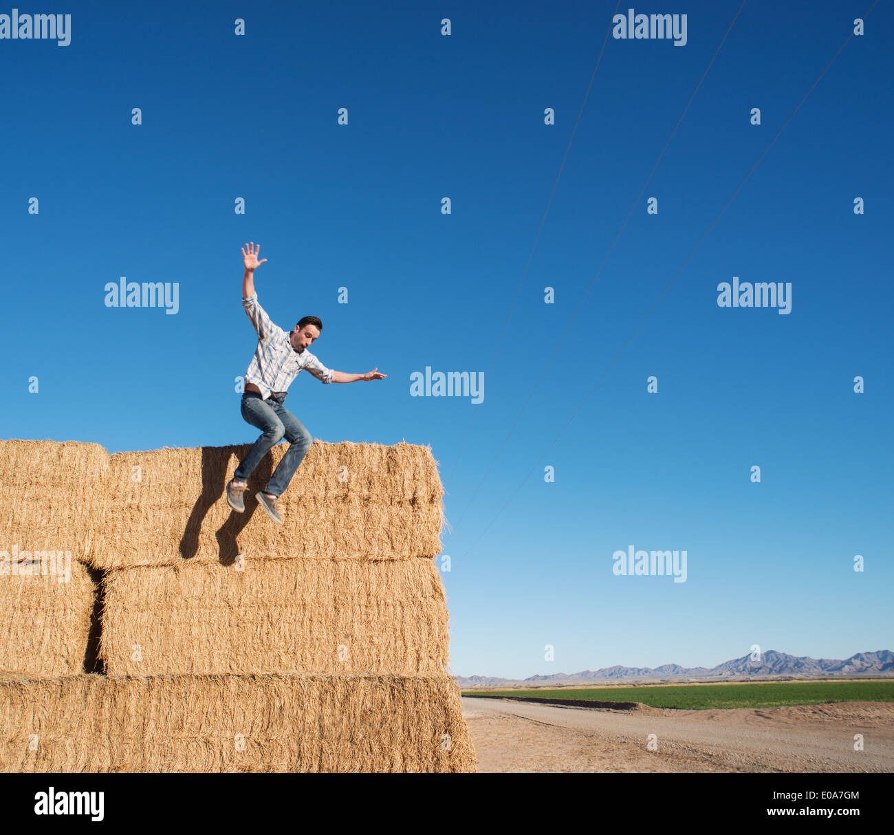 Mann springt aus Heuhaufen Stockfoto