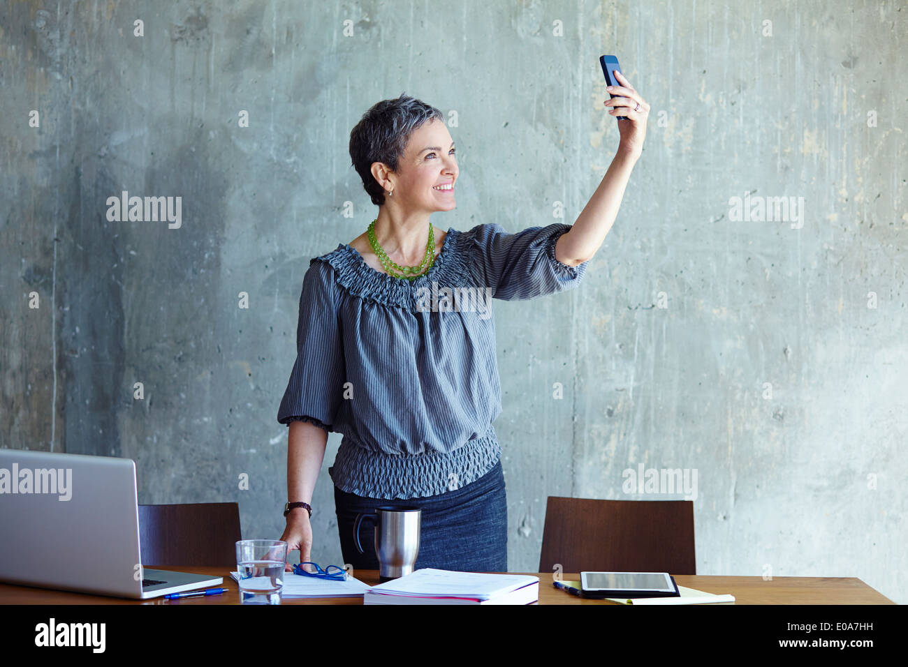 Reife Geschäftsfrau unter Selbstporträt im Büro Stockfoto