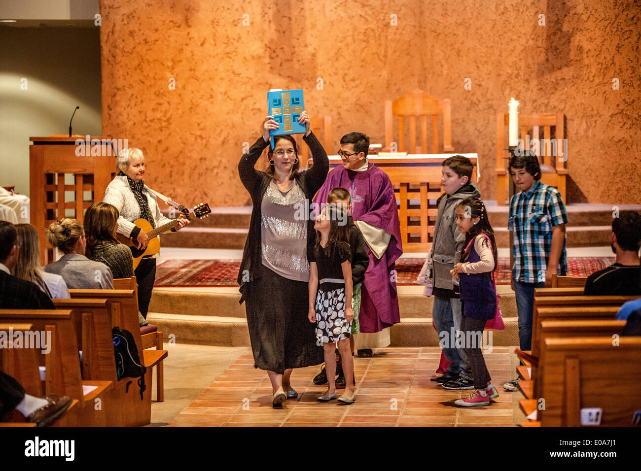 Im Anschluss an das Anfangsgebet an Masse Kinder Gemeindemitglieder sind führen zu ein spezielles Kindermenü Wortgottesdienst am Laguna Niguel, CA, katholische Kirche. Beachten Sie Bibel Führer durchführte und vietnamesische amerikanische Priester gekleidet. Stockfoto