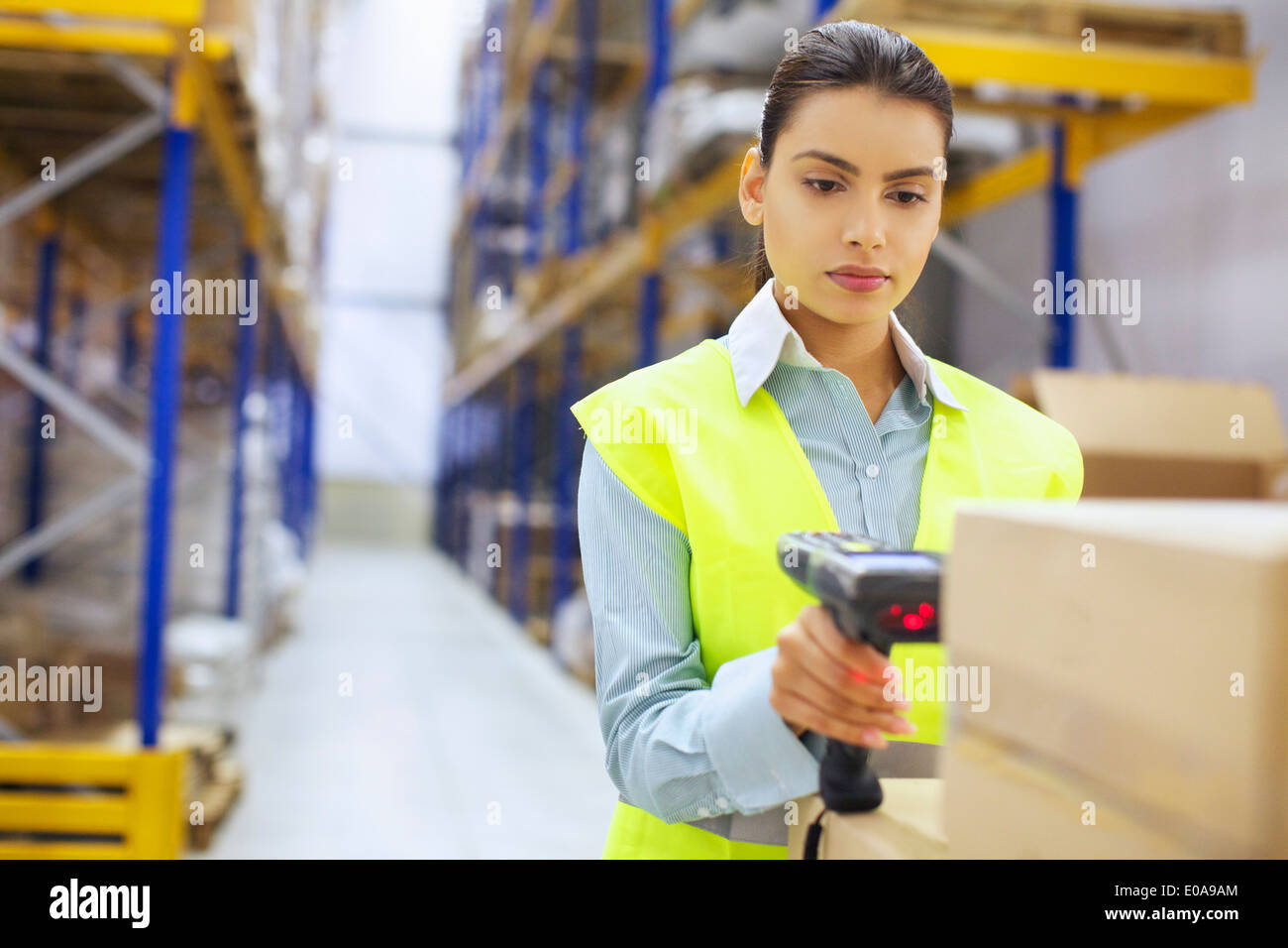 Junge Frau mit Barcode-Leser im Auslieferungslager Stockfoto