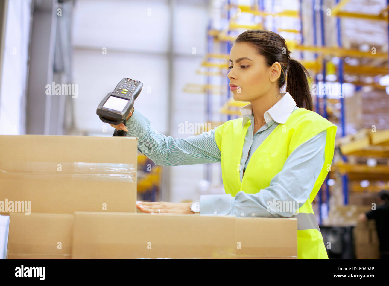 Junge Frau mit Barcode-Lesegerät im Auslieferungslager Stockfoto