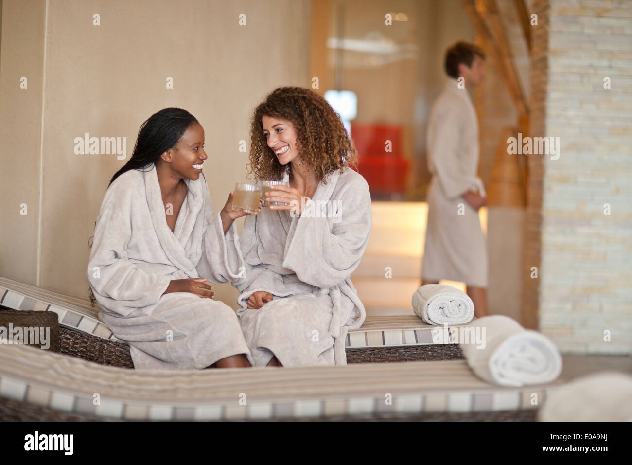 Zwei junge Frauen im Chat auf Liegestühlen im spa Stockfoto