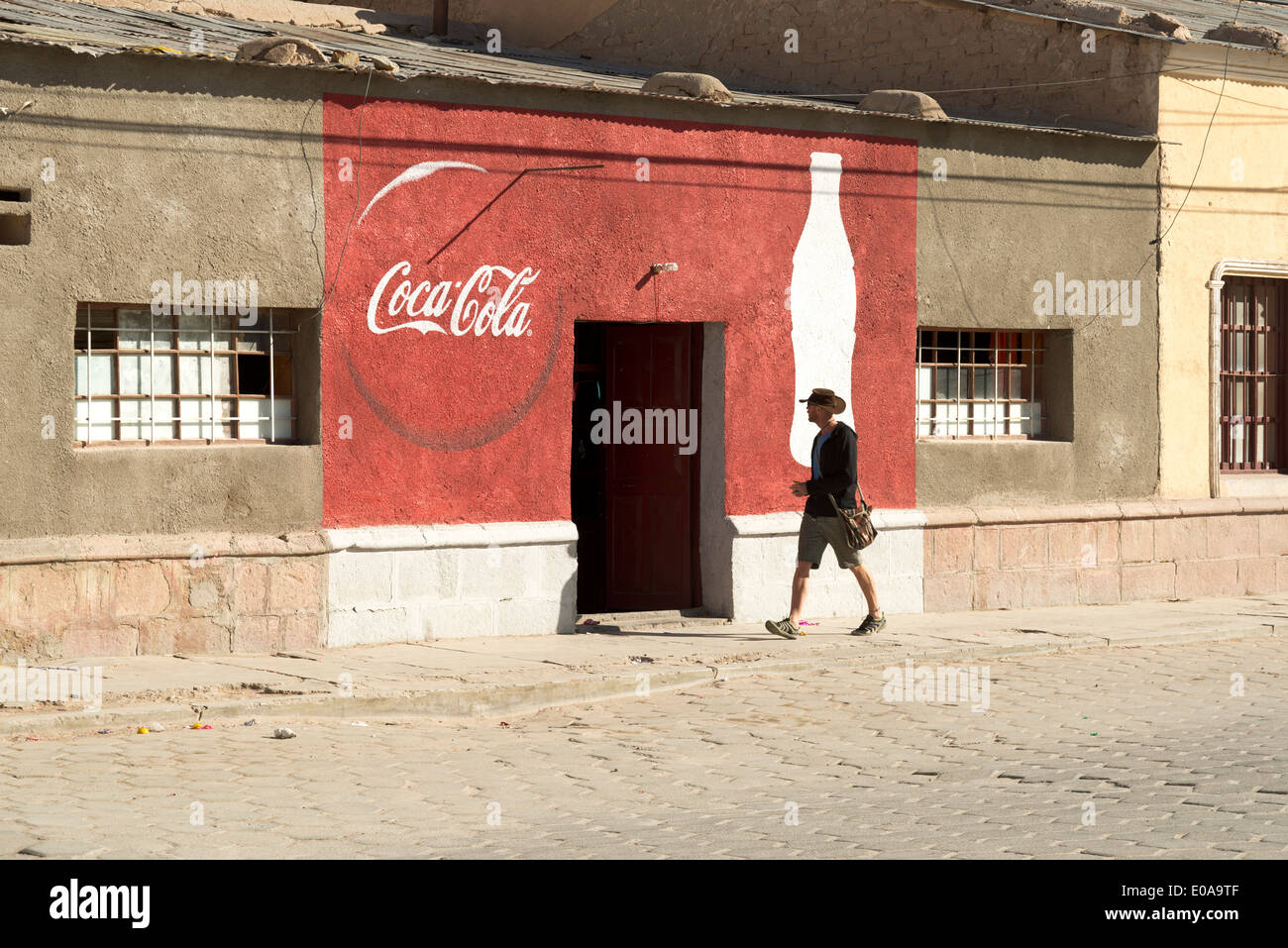 Mann zu Fuß vorbei an einem Haus gemalt wie ein Coca Cola-Werbung. Stockfoto