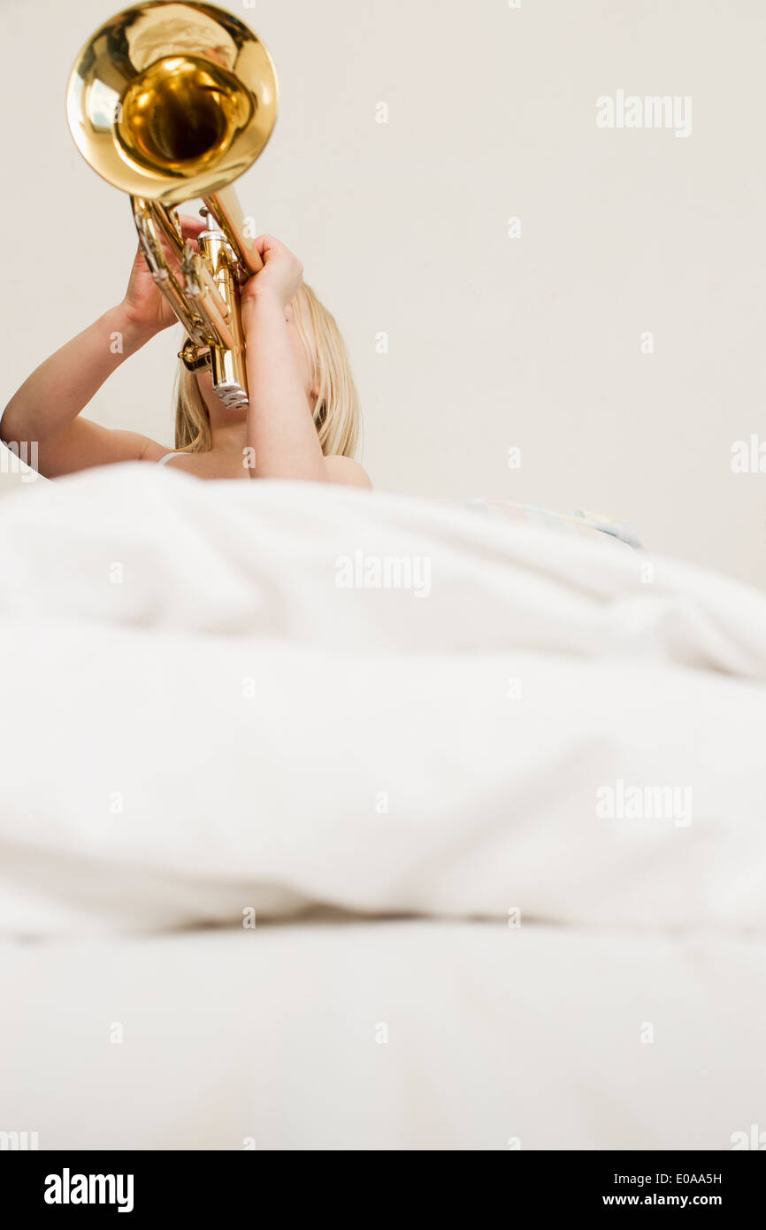 Mädchen spielen Trompete im Bett Stockfoto