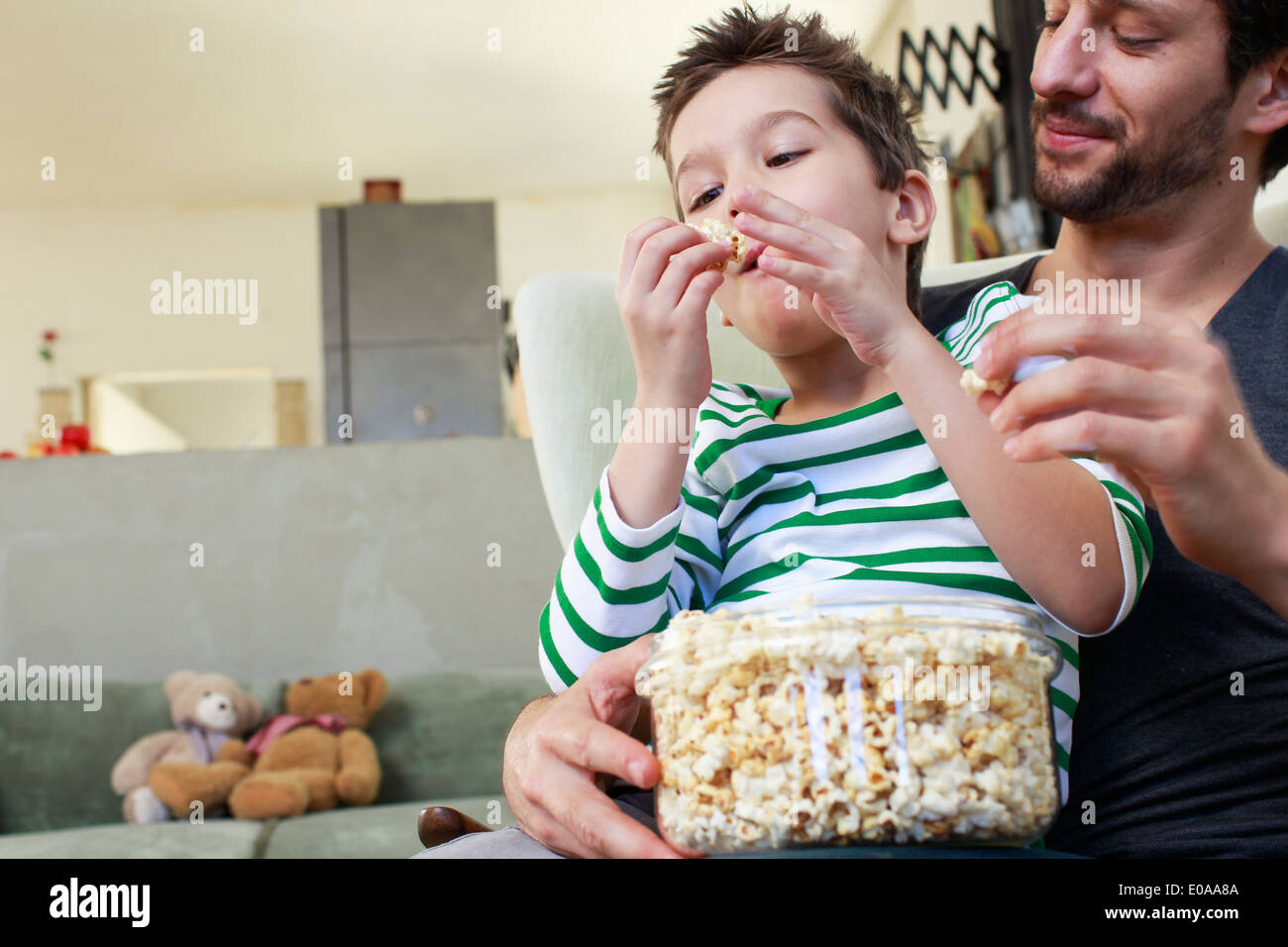 Vater und Sohn teilen Popcorn im Wohnzimmer Stockfoto