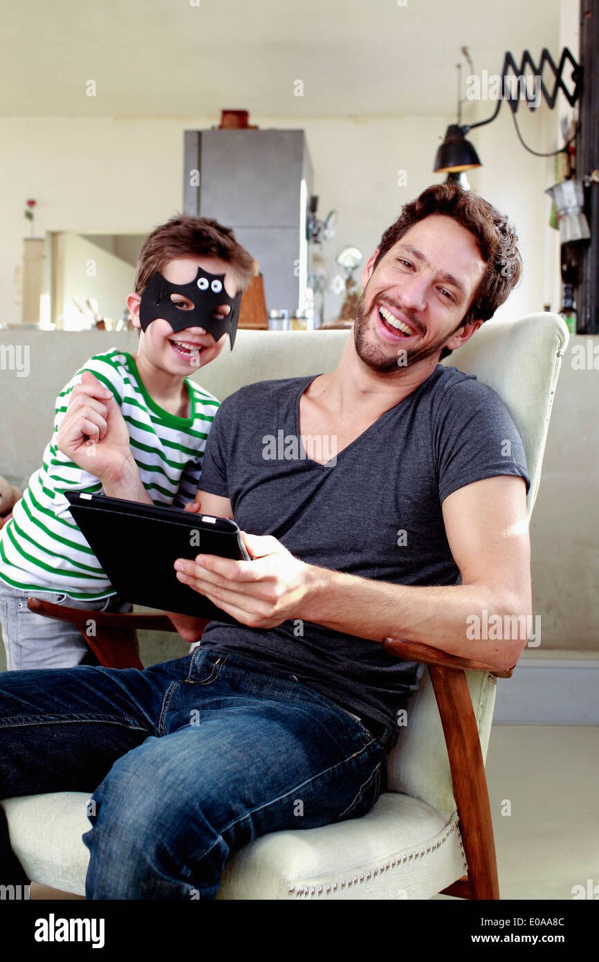 Vater und Sohn sitzen auf Stühlen mit digital-Tablette Stockfoto