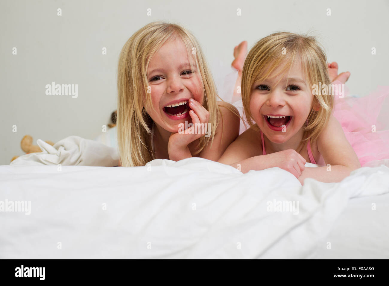 Porträt von zwei jungen Schwestern auf Vorderseite im Bett liegend Stockfoto