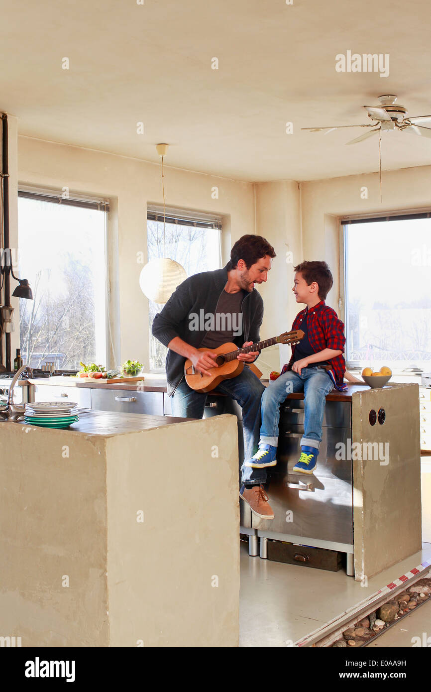 Vater und seinem kleinen Sohn spielt Gitarre in Küche Stockfoto