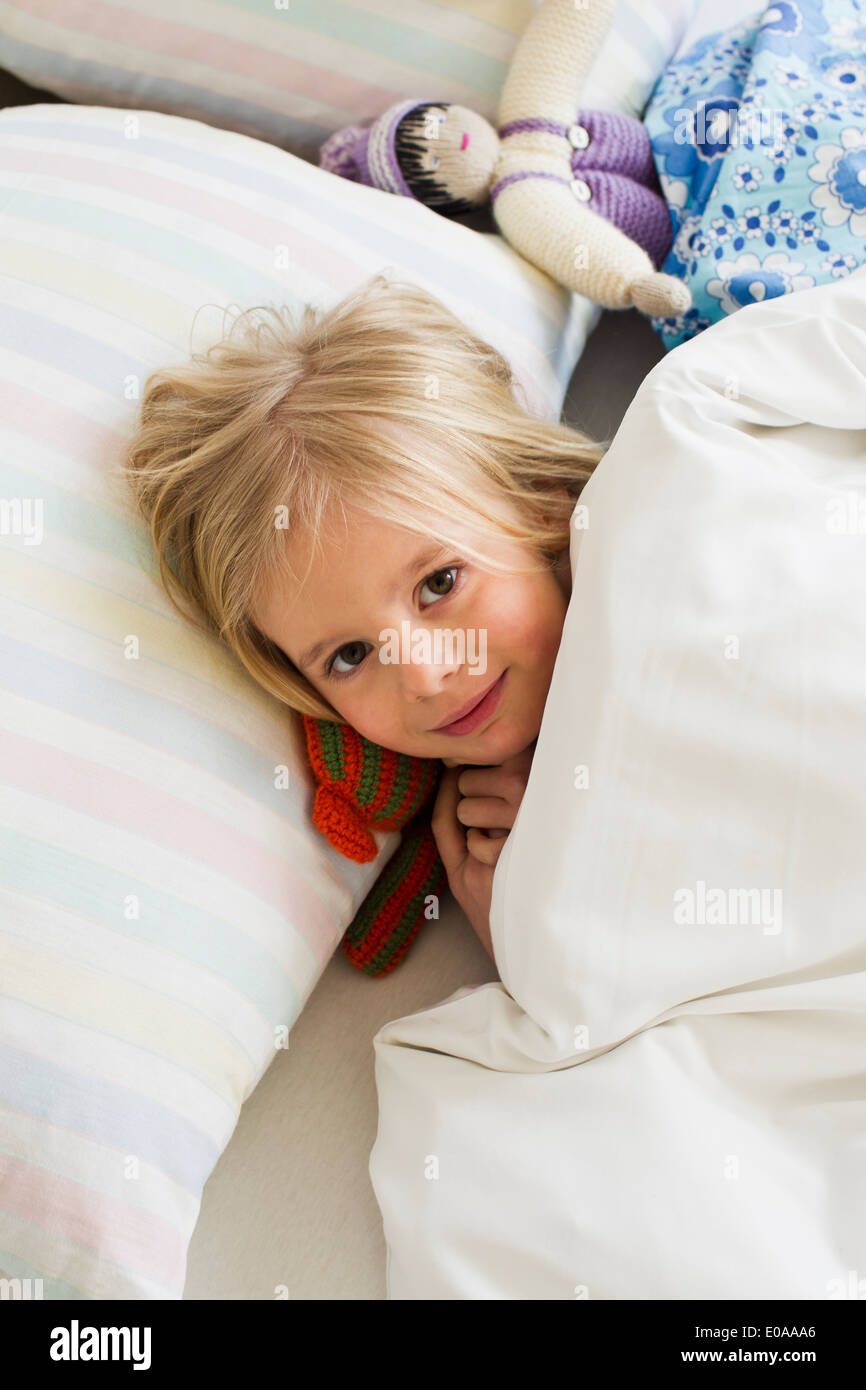 Porträt des jungen Mädchens liegen im Bett mit Puppe Stockfoto