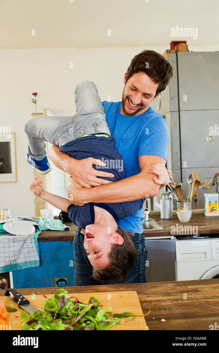 Vater Holding jungen Sohn kopfüber in Küche Stockfoto