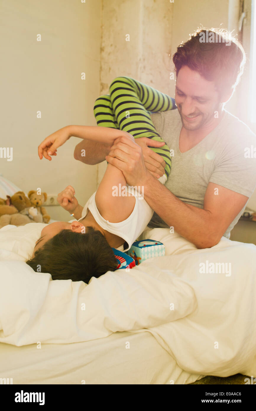 Vater und Sohn spielen kämpfen auf Bett Stockfoto