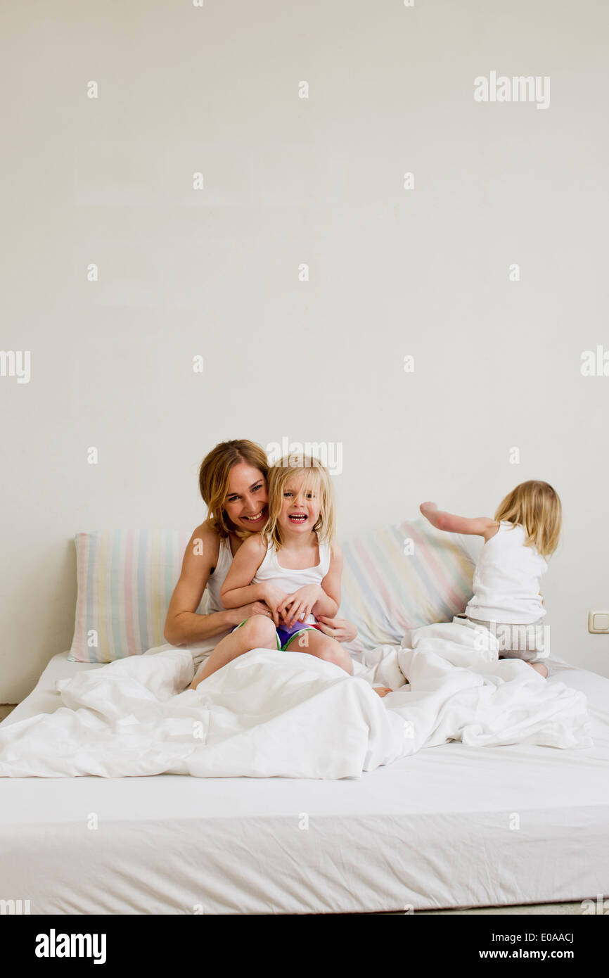 Porträt von Mitte Erwachsene Frau mit zwei Töchtern im Bett sitzen Stockfoto