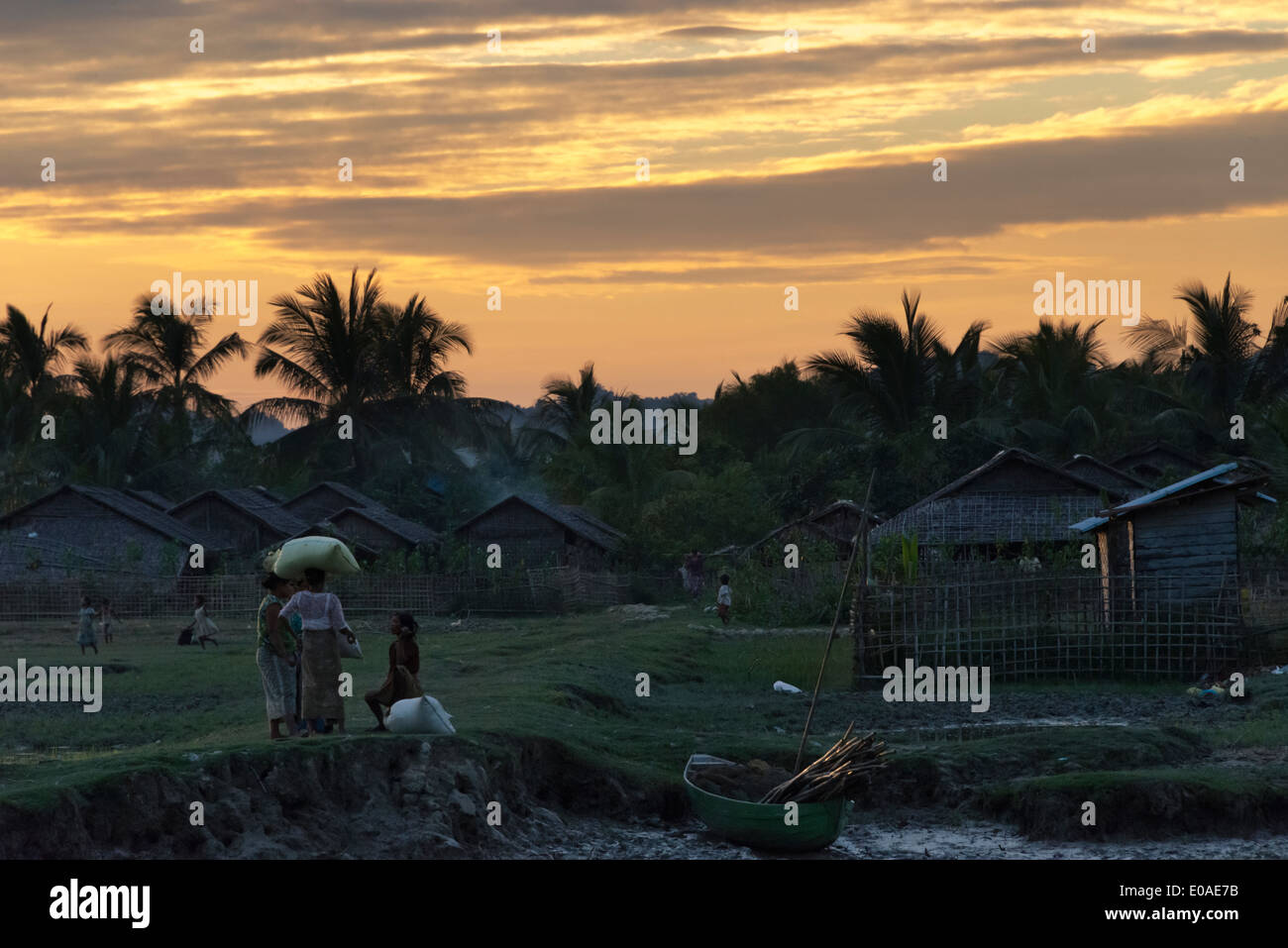 Bambushaus mit Palm Leaf Dach entlang des Flusses Kaladan bei Sonnenuntergang, Sittwe, Rakhine State in Myanmar Stockfoto