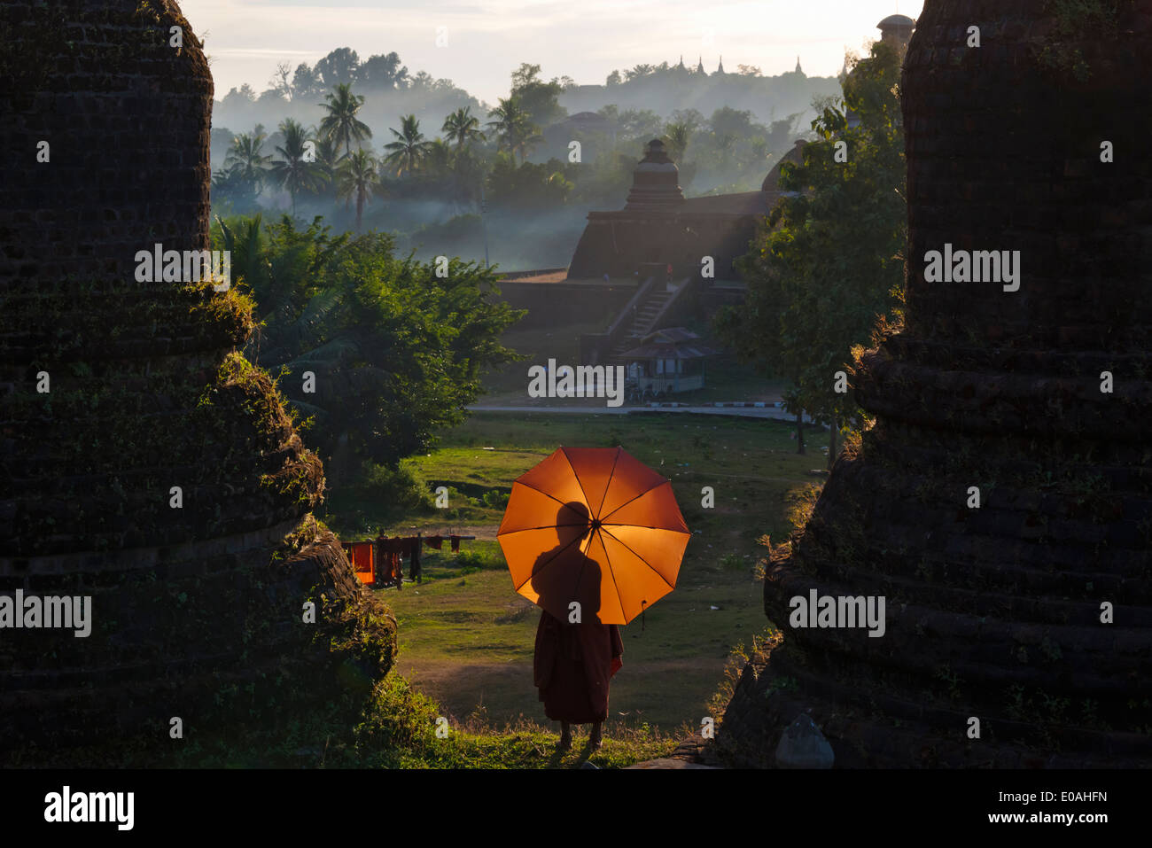 Mönch mit roten Regenschirm am Andaw-Thein Tempel bei Sonnenuntergang, Mrauk-U, Rakhine State in Myanmar Stockfoto