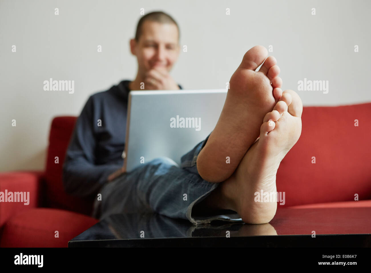 Mitte erwachsenen Mannes entspannend auf Sofa in Laptop vertieft Stockfoto