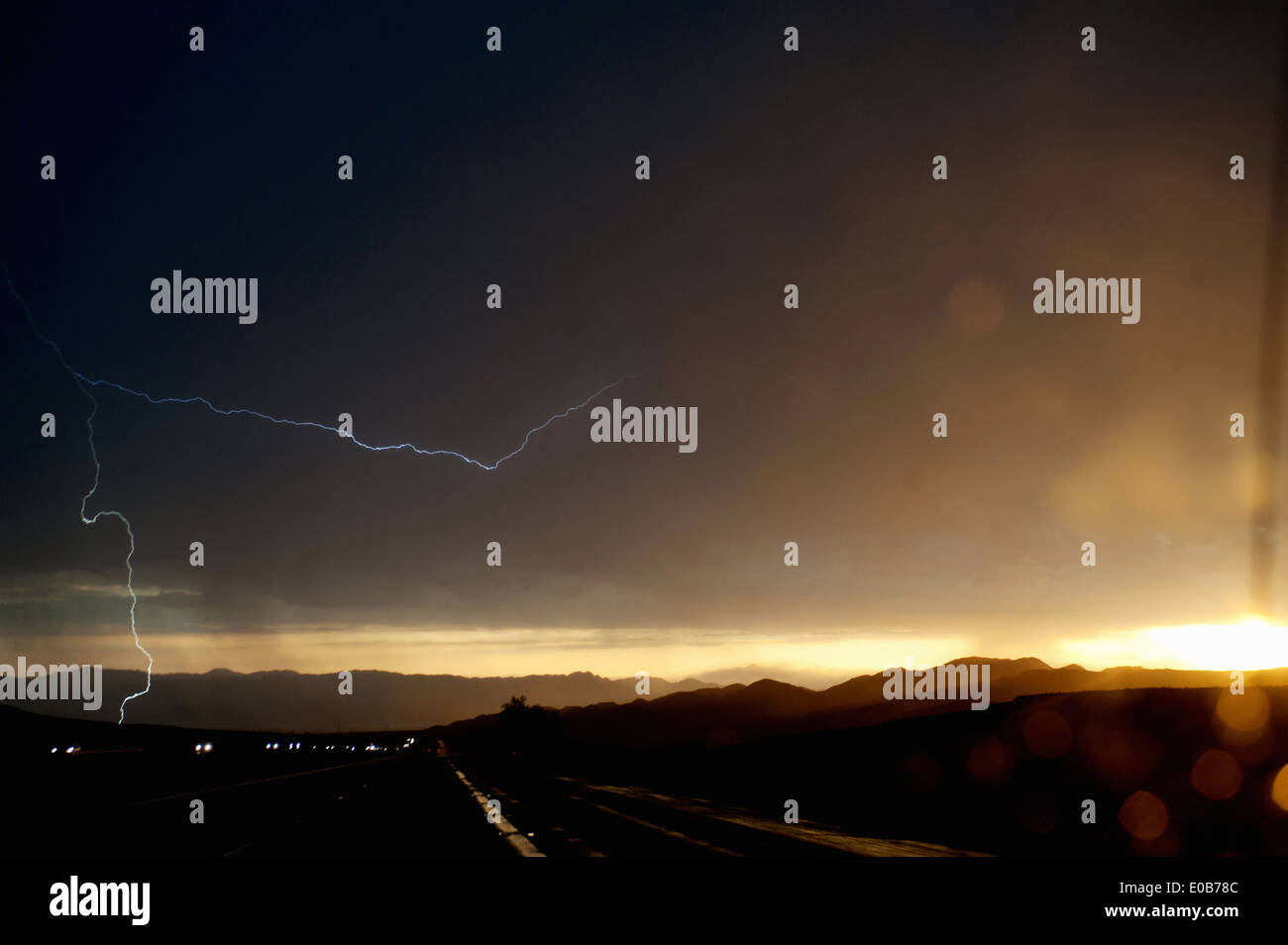 Autoscheinwerfer auf Silhouette Autobahn bei Gewitter Stockfoto