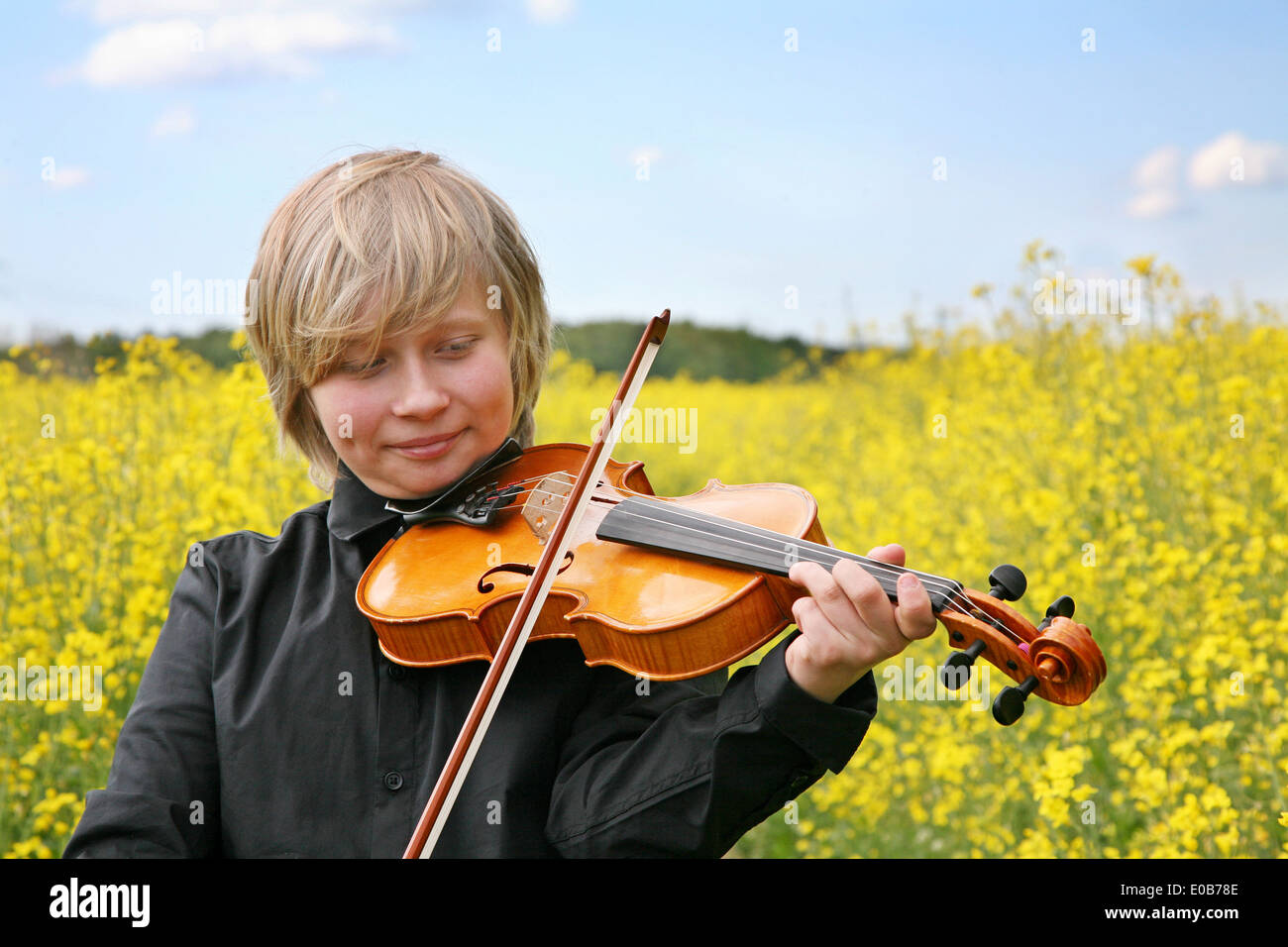 Teenager mit Geige im Rapsfeld Stockfoto