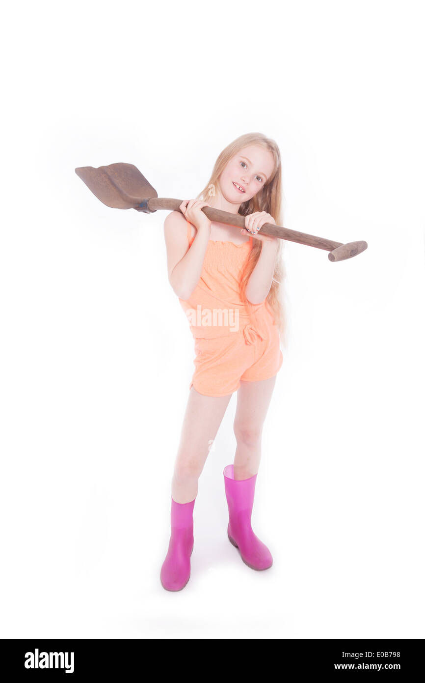 junge blonde Mädchen mit Schaufel im Studio vor weißem Hintergrund stehen Stockfoto