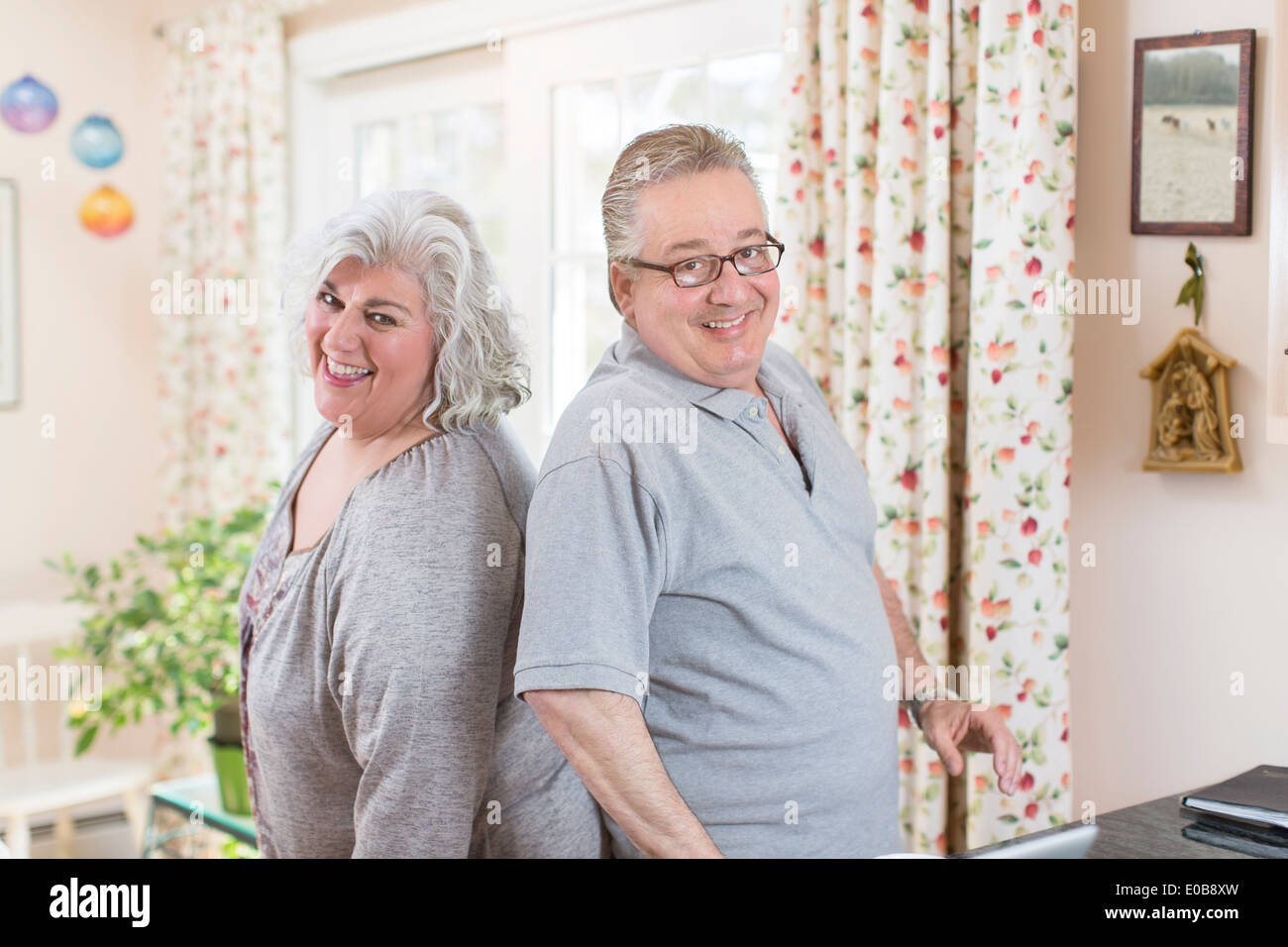 Porträt des reifes Paar Rücken an Rücken im Wohnzimmer Stockfoto