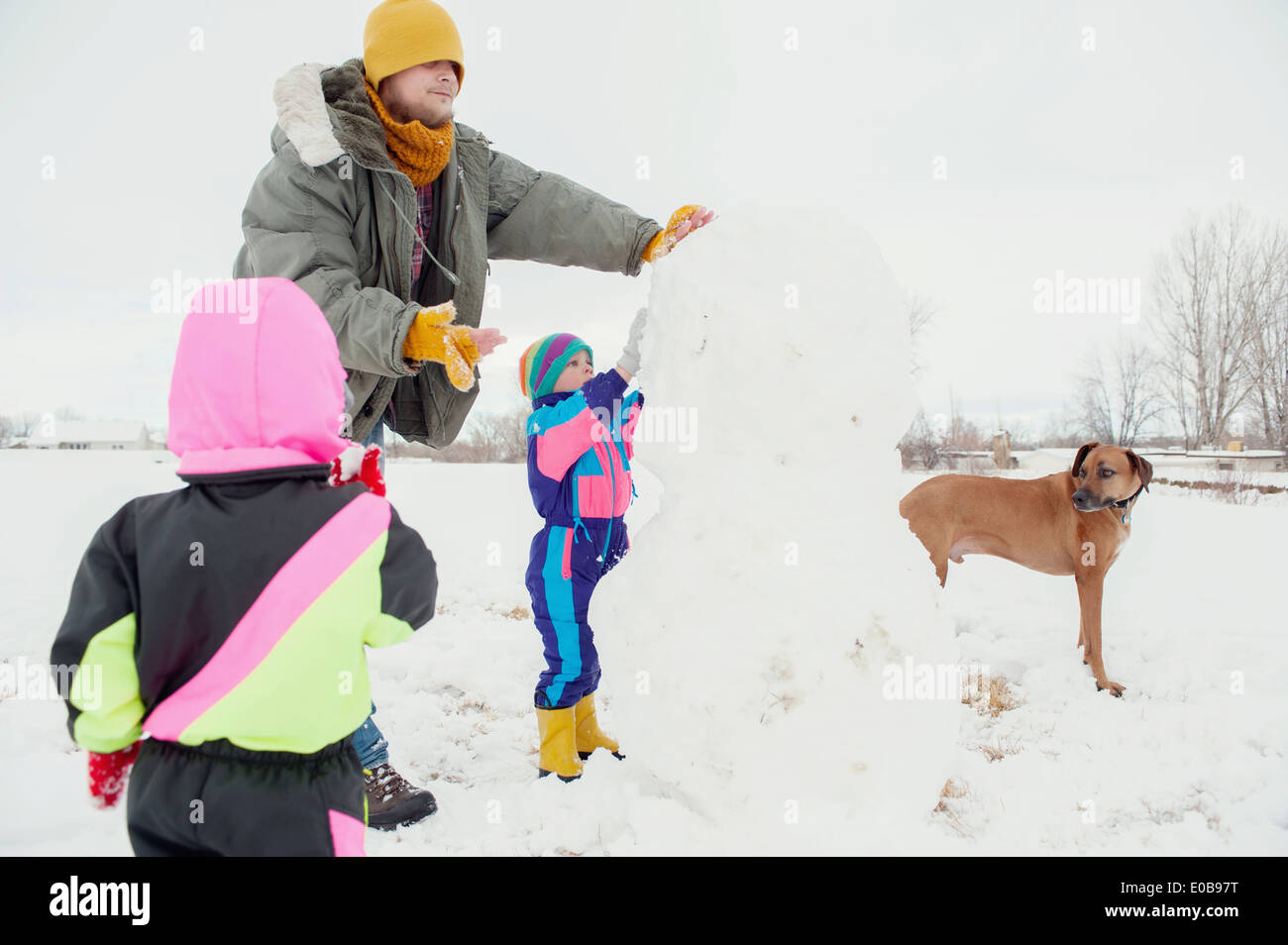 Vater und Kinder Schneemann bauen Stockfoto