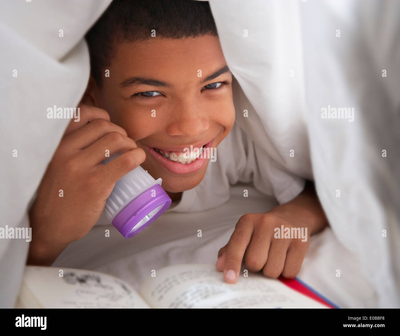 Junge Lesebuch mit Taschenlampe unter der Bettdecke Stockfoto