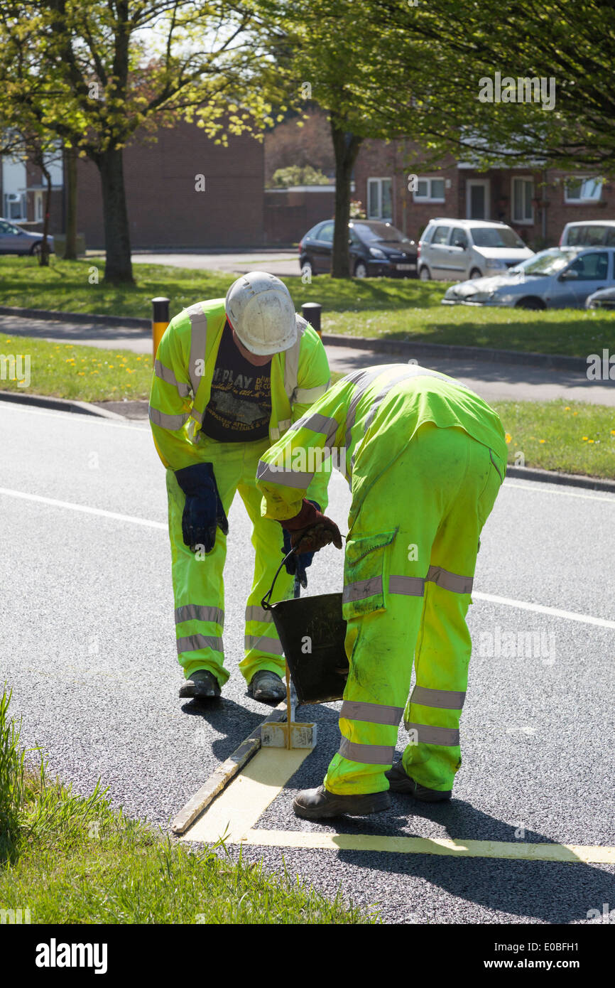 Zwei Arbeiter Malerei Zick-Zack-gelbe Linien auf neu asphaltierte Straße. Stockfoto