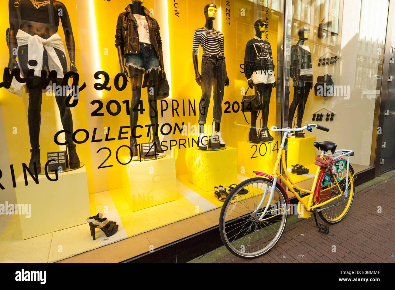 AMSTERDAM, Niederlande - 19. März 2014: Fahrradständer in der Nähe moderner gelbe Schaufenster mit schwarz Schaufensterpuppen Stockfoto