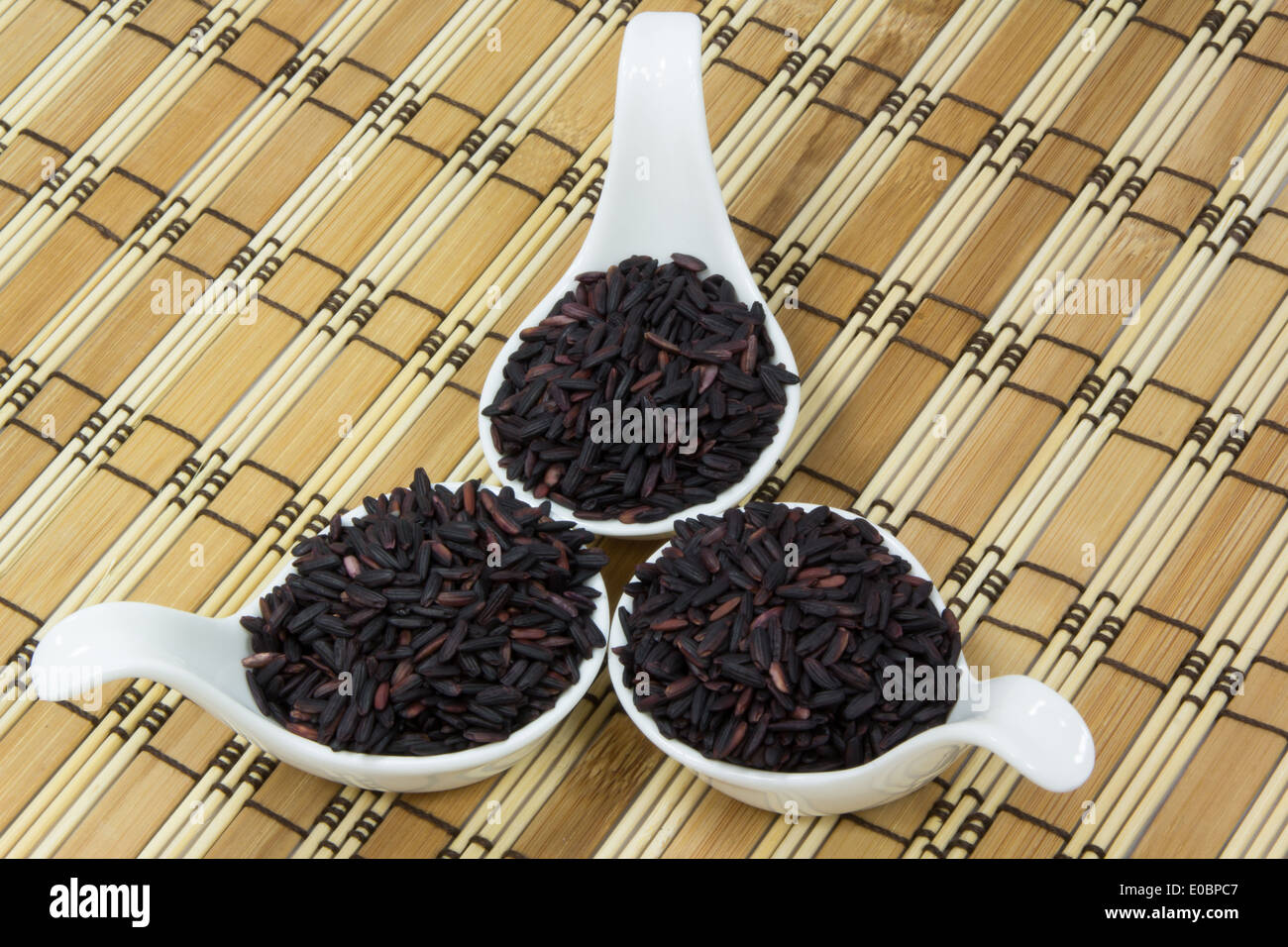 Schwarzer Reis in Holz Schlag und Keramik Löffel mit Bierdeckel Stockfoto